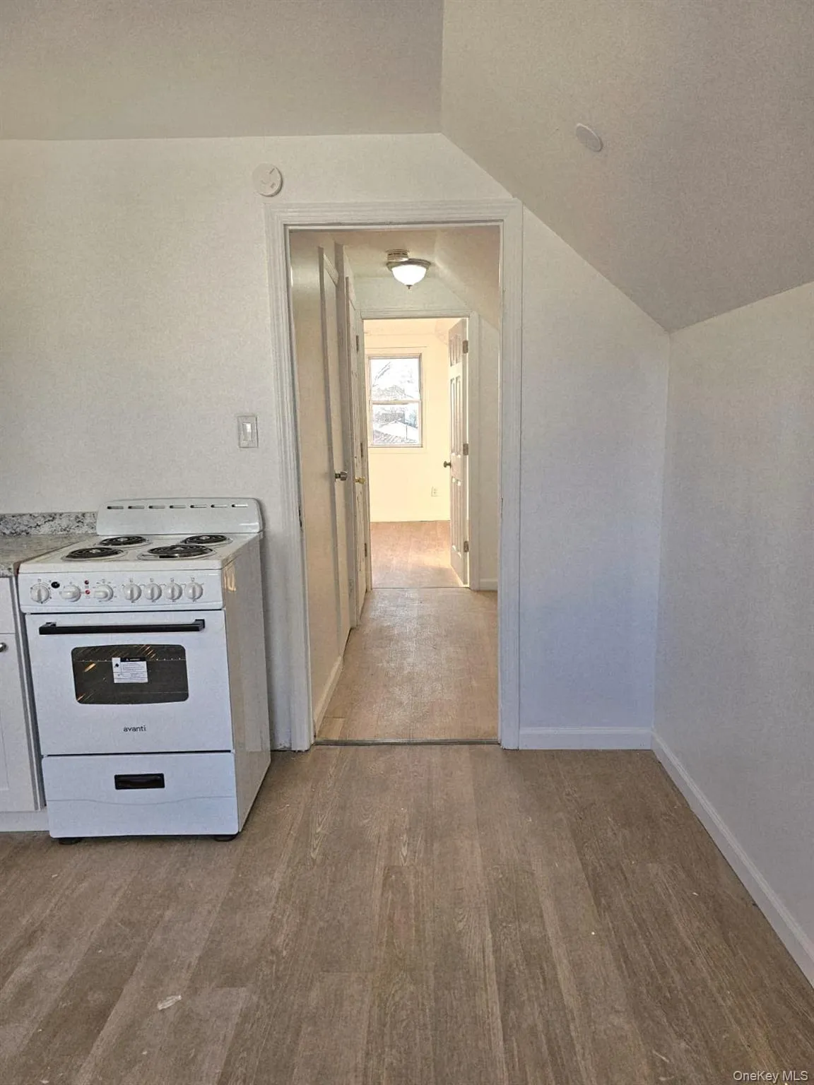 Corridor featuring light wood-style floors and lofted ceiling Corridor featuring light wood-style floors and lofted ceiling