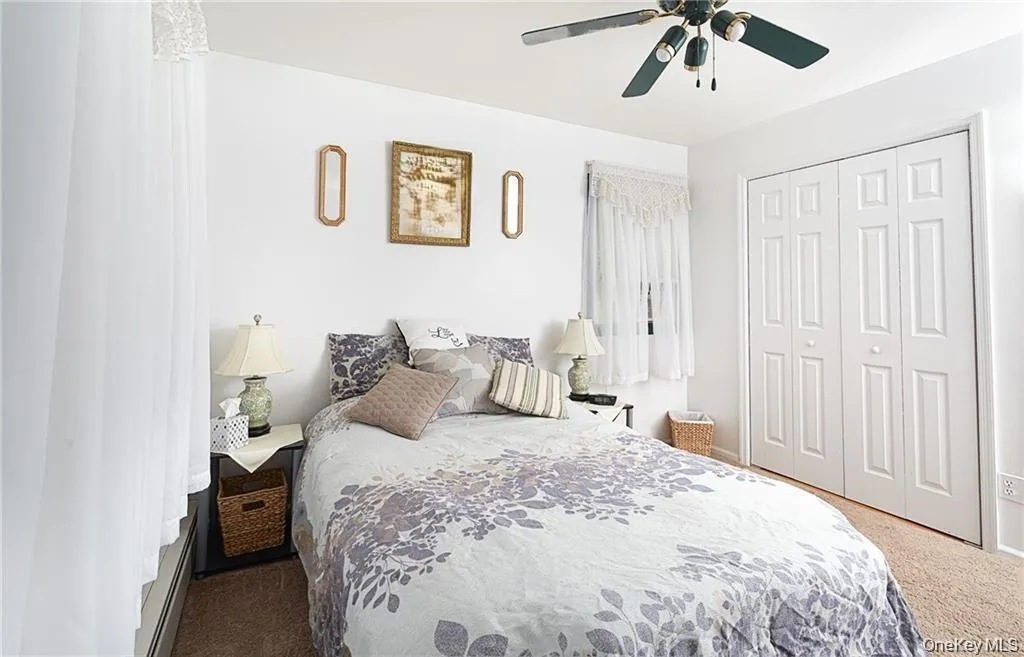 Bedroom with carpet flooring, a closet, a ceiling fan, and baseboard heating Bedroom with carpet flooring, a closet, a ceiling fan, and baseboard heating