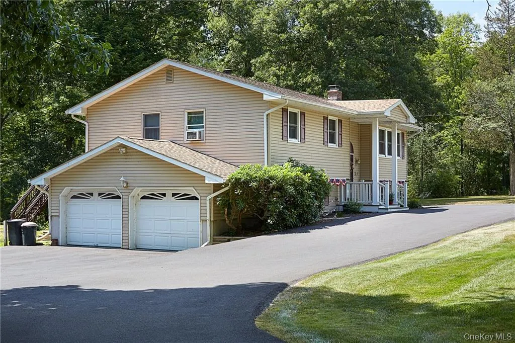 Raised ranch featuring a chimney, driveway, roof with shingles, and a front yard Raised ranch featuring a chimney, driveway, roof with shingles, and a front yard
