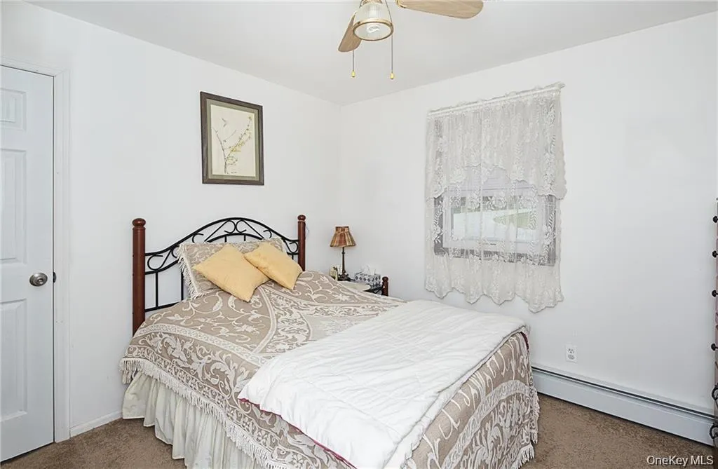 Bedroom with a baseboard radiator, carpet floors, and ceiling fan Bedroom with a baseboard radiator, carpet floors, and ceiling fan