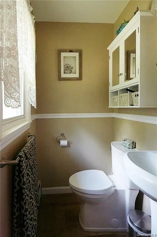 Half bath featuring toilet and dark wood finished floors Half bath featuring toilet and dark wood finished floors