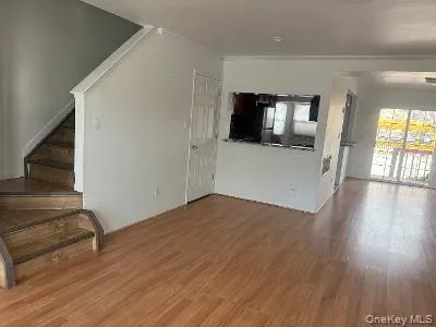 Unfurnished living room featuring dark wood-type flooring and stairway Unfurnished living room featuring dark wood-type flooring and stairway