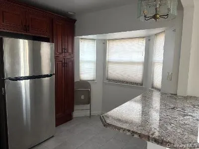 Kitchen with freestanding refrigerator, plenty of natural light, a chandelier, and stone counters Kitchen with freestanding refrigerator, plenty of natural light, a chandelier, and stone counters