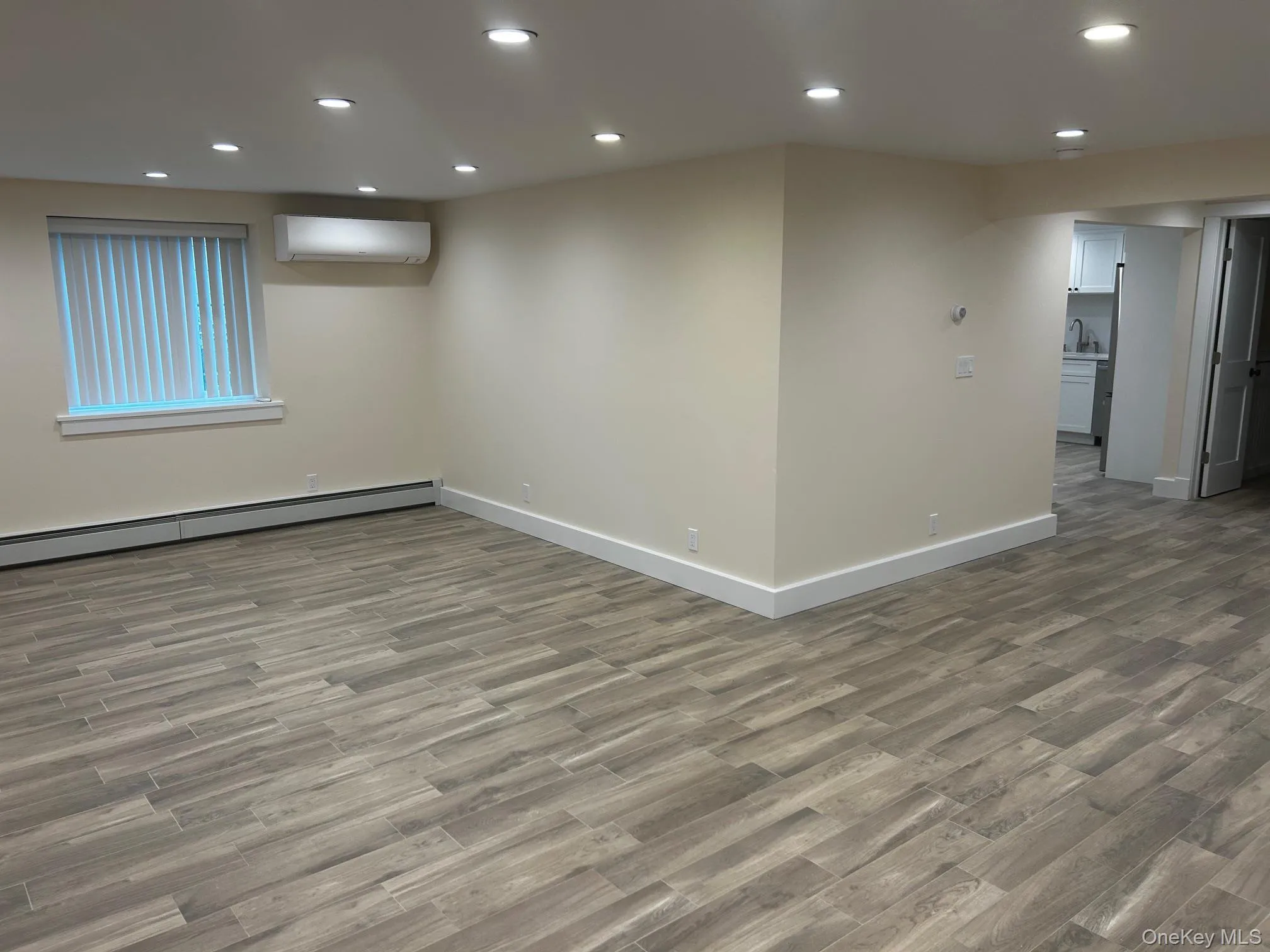 Living room with recessed lighting, dark wood finished floors, a wall mounted air conditioner, and a baseboard heating unit Living room with recessed lighting, dark wood finished floors, a wall mounted air conditioner, and a baseboard heating unit