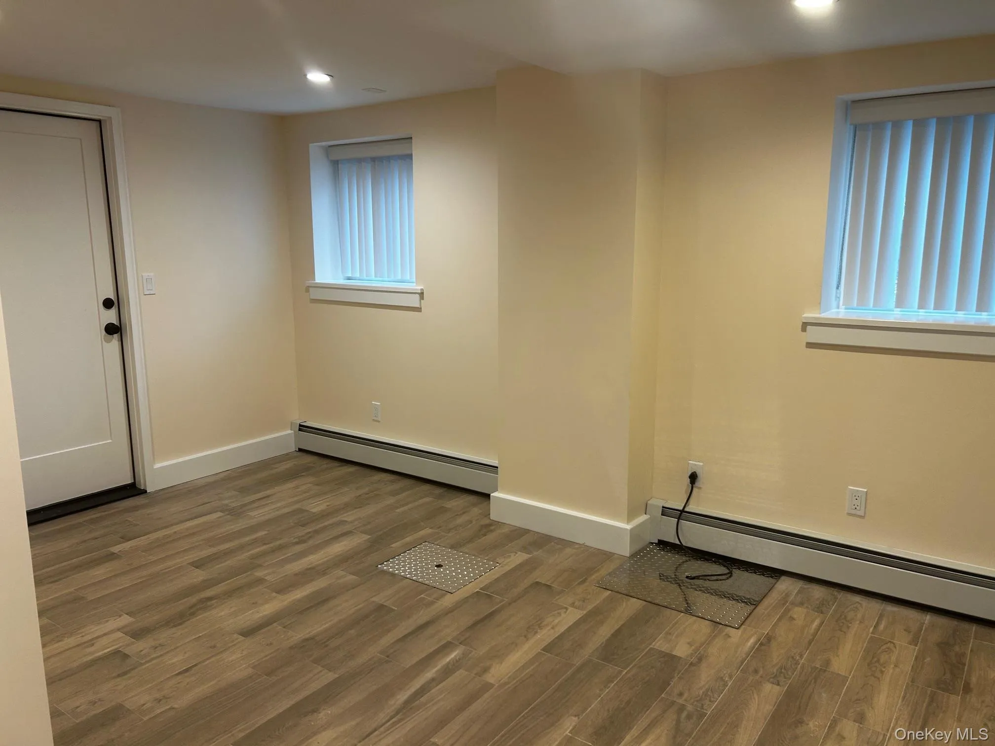 Bedroom featuring dark wood-style flooring, a baseboard heating unit, and recessed lighting Bedroom featuring dark wood-style flooring, a baseboard heating unit, and recessed lighting