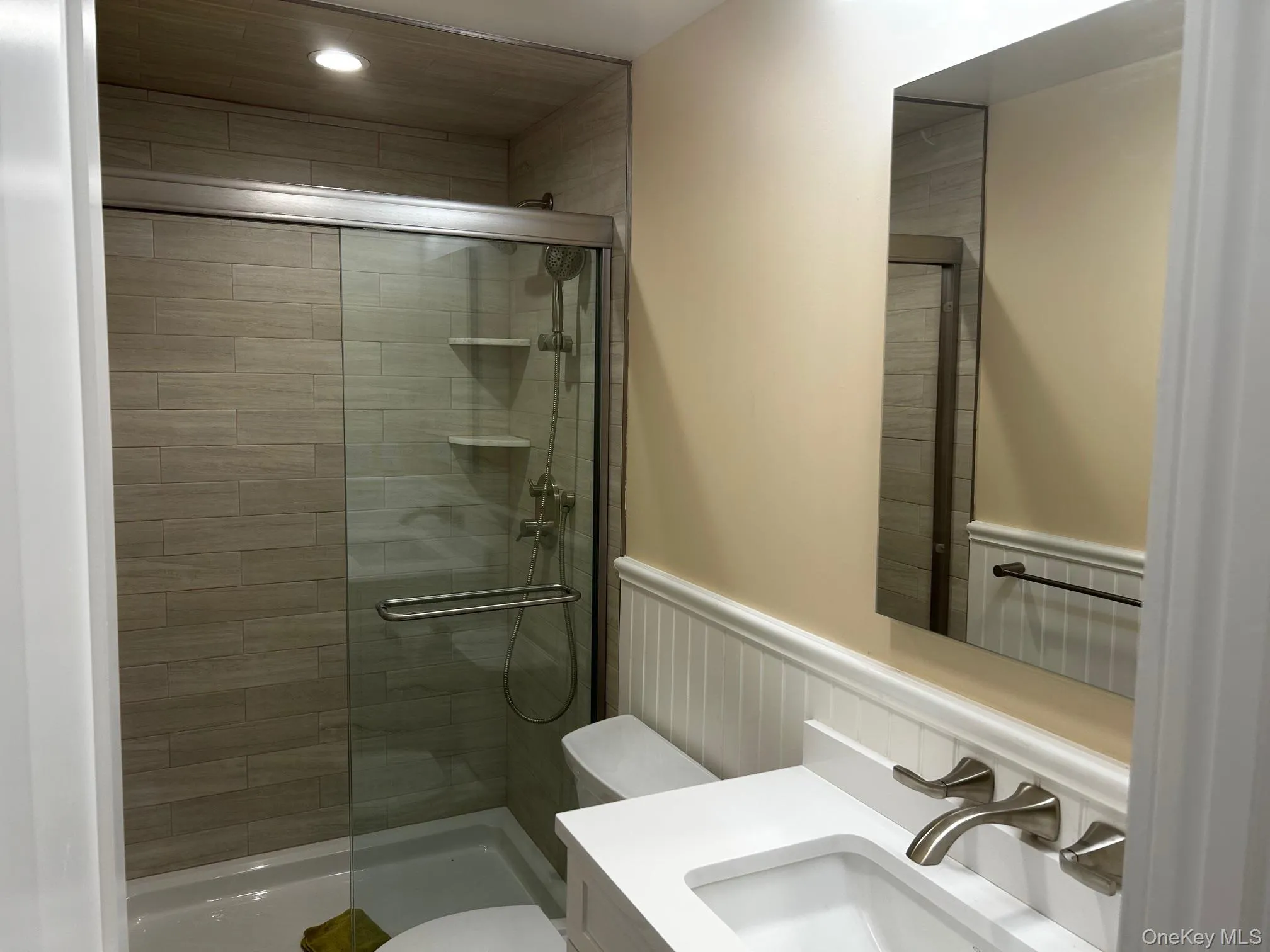 Bathroom with vanity, a shower stall, and a wainscoted wall Bathroom with vanity, a shower stall, and a wainscoted wall