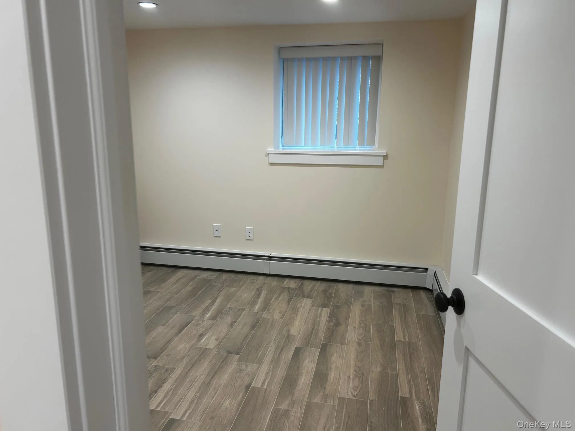 Bedroom featuring wood finished floors, a baseboard heating unit, and recessed lighting Bedroom featuring wood finished floors, a baseboard heating unit, and recessed lighting