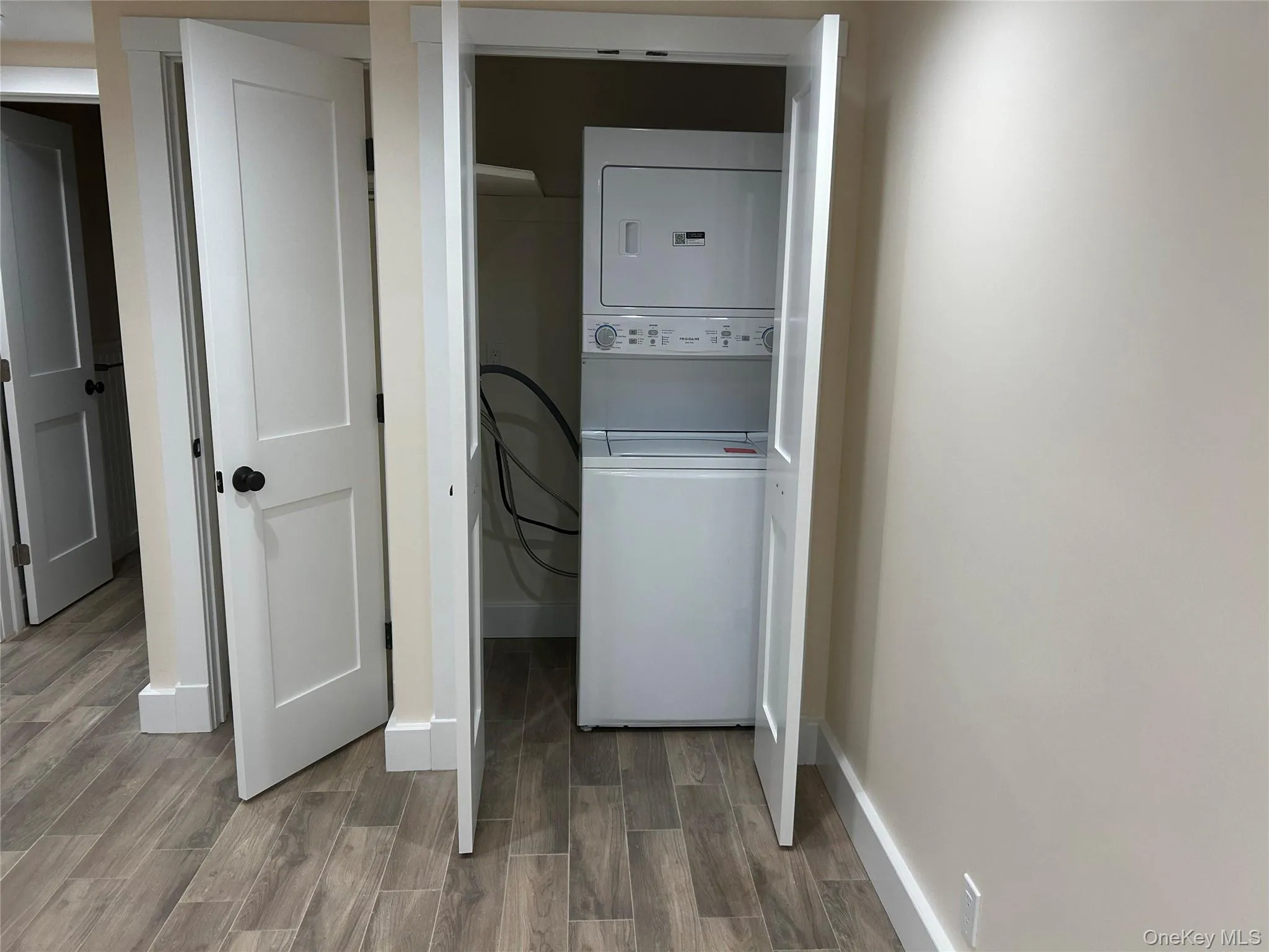 Laundry room with wood finish floors and stacked washer / drying machine Laundry room with wood finish floors and stacked washer / drying machine