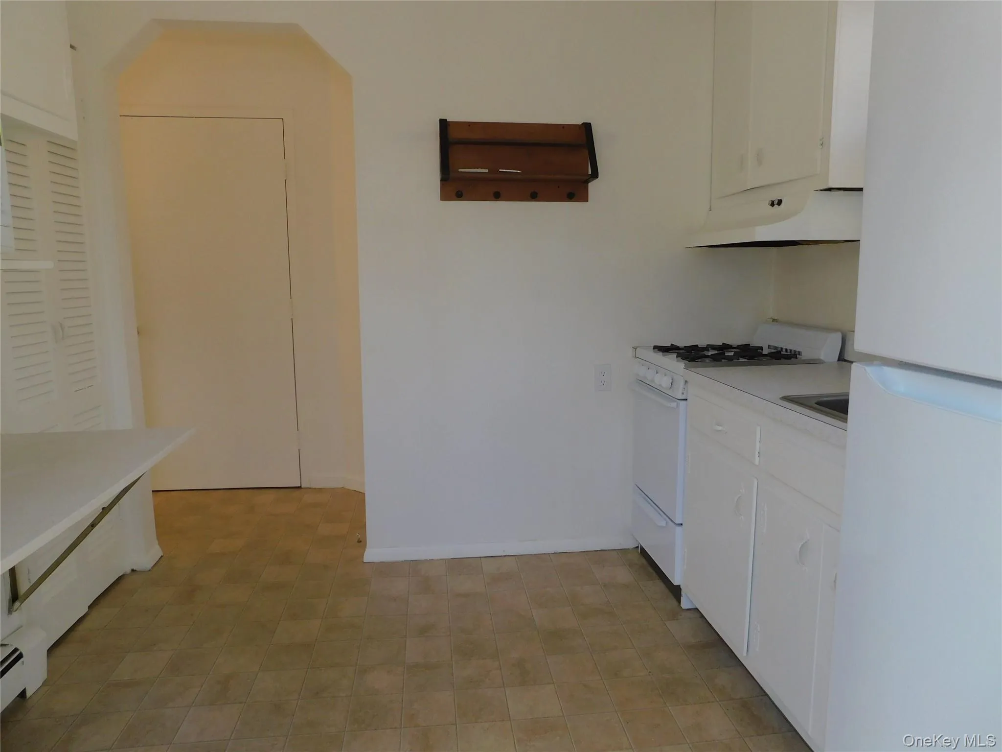 Kitchen with white cabinets, white appliances, light countertops, under cabinet range hood, and light floors Kitchen with white cabinets, white appliances, light countertops, under cabinet range hood, and light floors