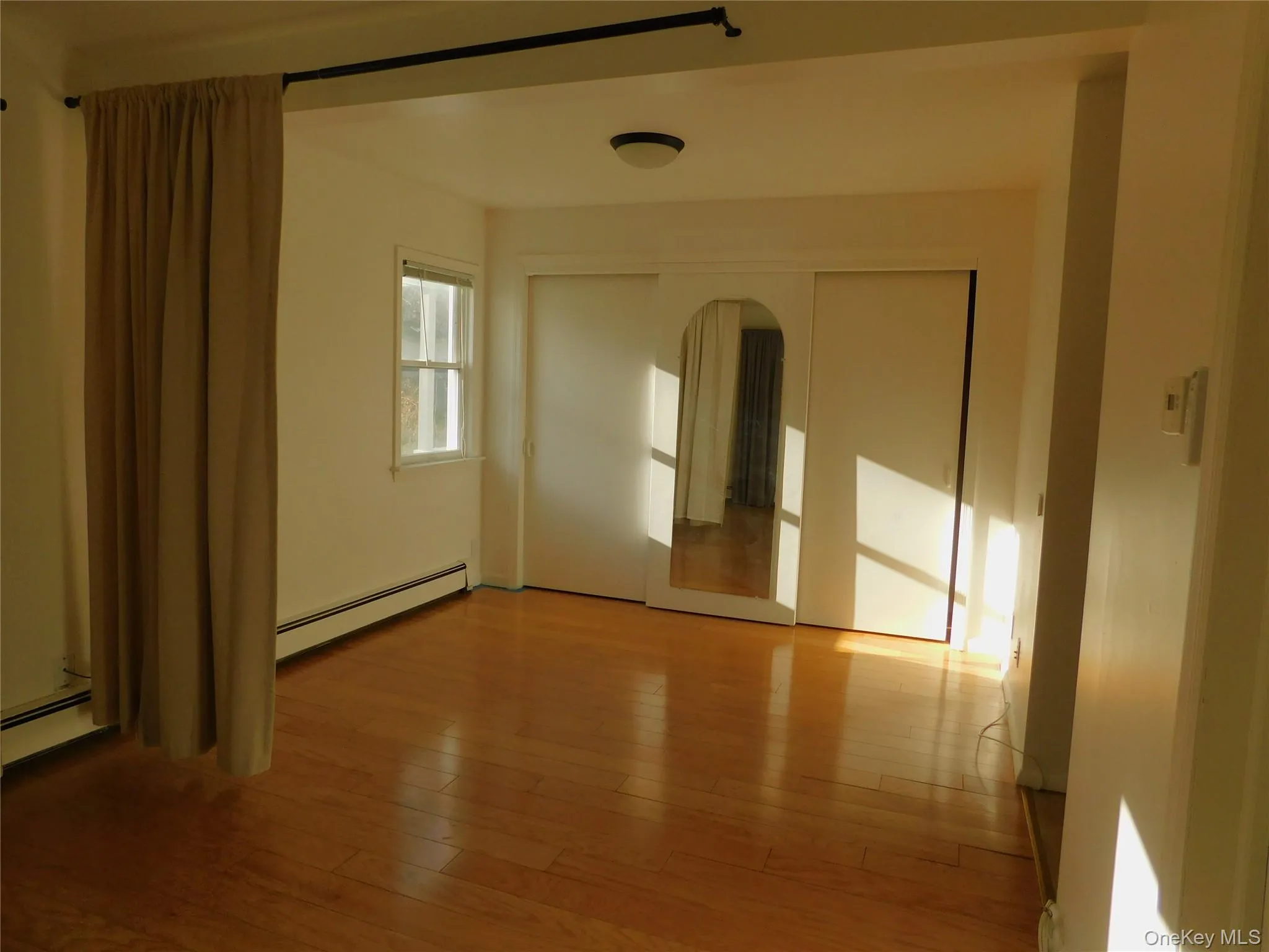 Unfurnished room featuring baseboard heating and light wood-style floors Unfurnished room featuring baseboard heating and light wood-style floors