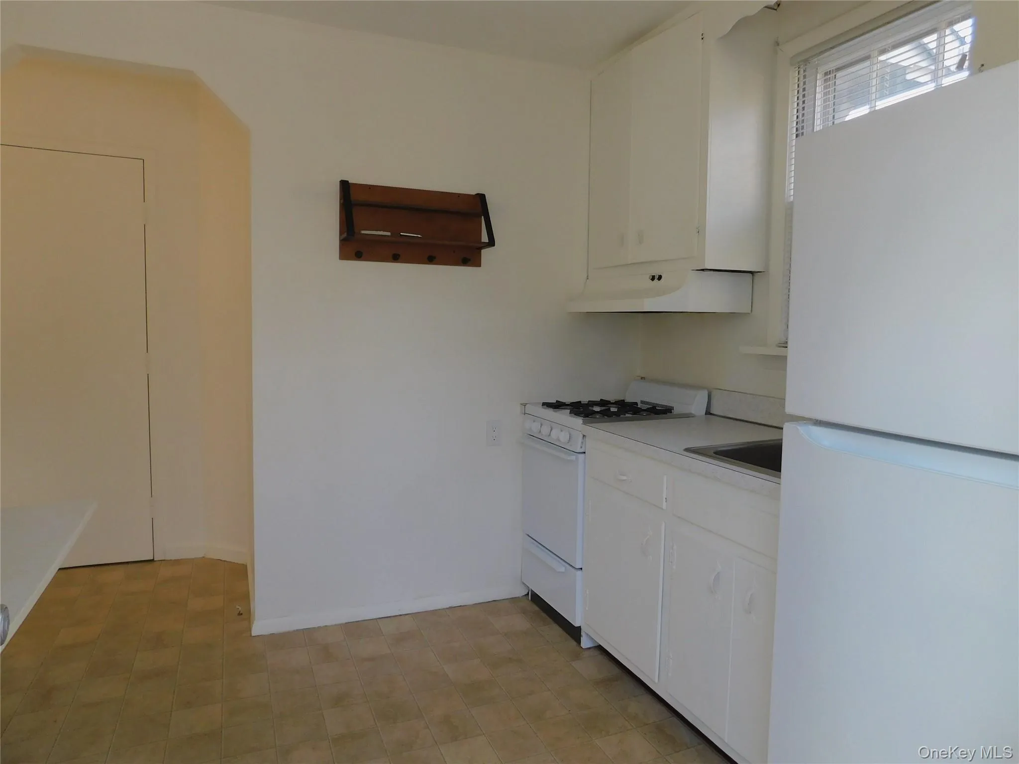 Kitchen featuring white appliances, white cabinets, light countertops, extractor fan, and light floors Kitchen featuring white appliances, white cabinets, light countertops, extractor fan, and light floors