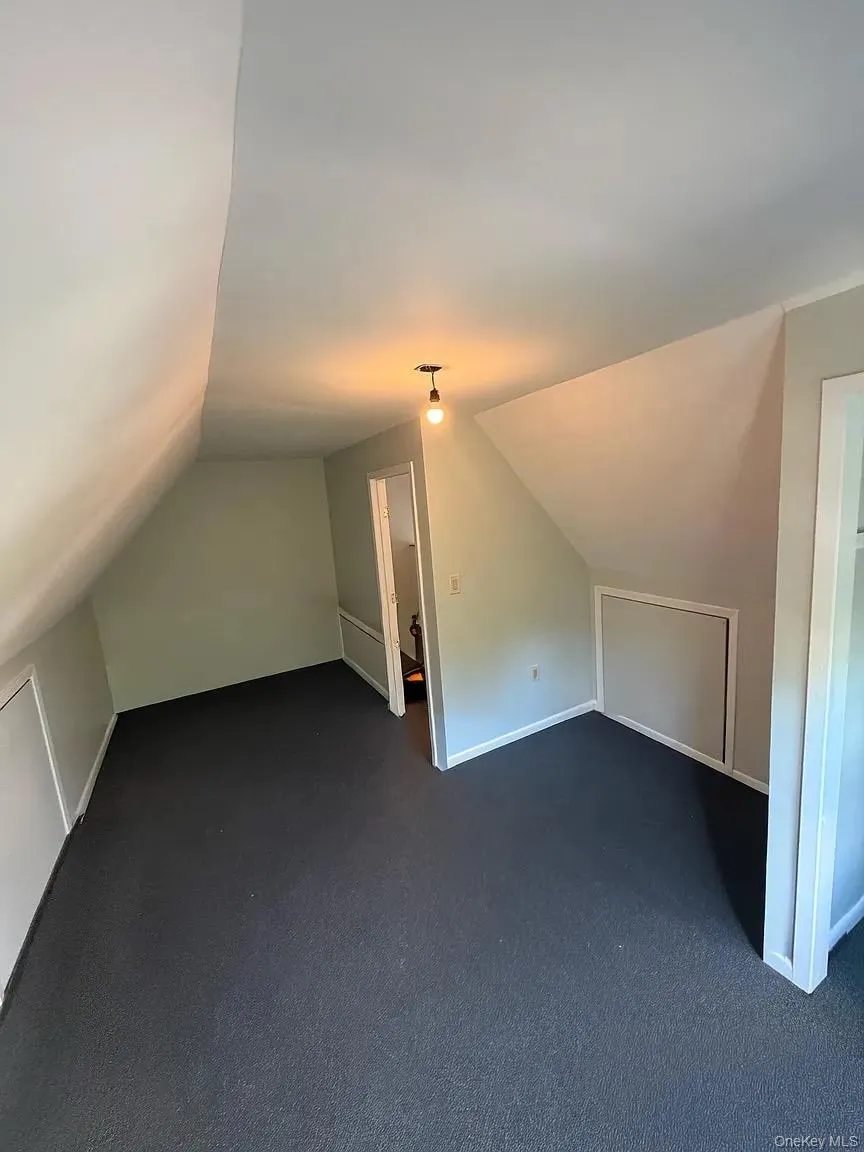 Additional living space featuring lofted ceiling and dark carpet Additional living space featuring lofted ceiling and dark carpet