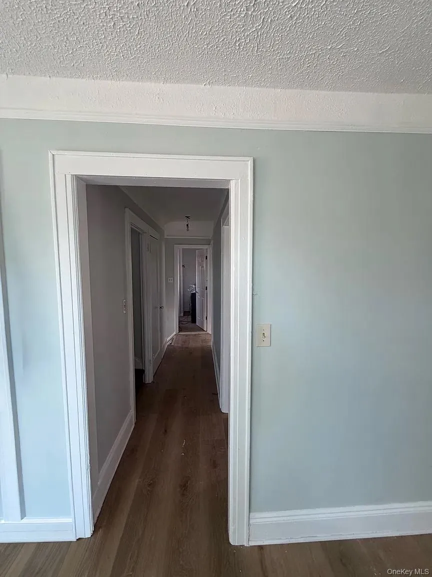 Hall featuring a textured ceiling and dark wood finished floors Hall featuring a textured ceiling and dark wood finished floors