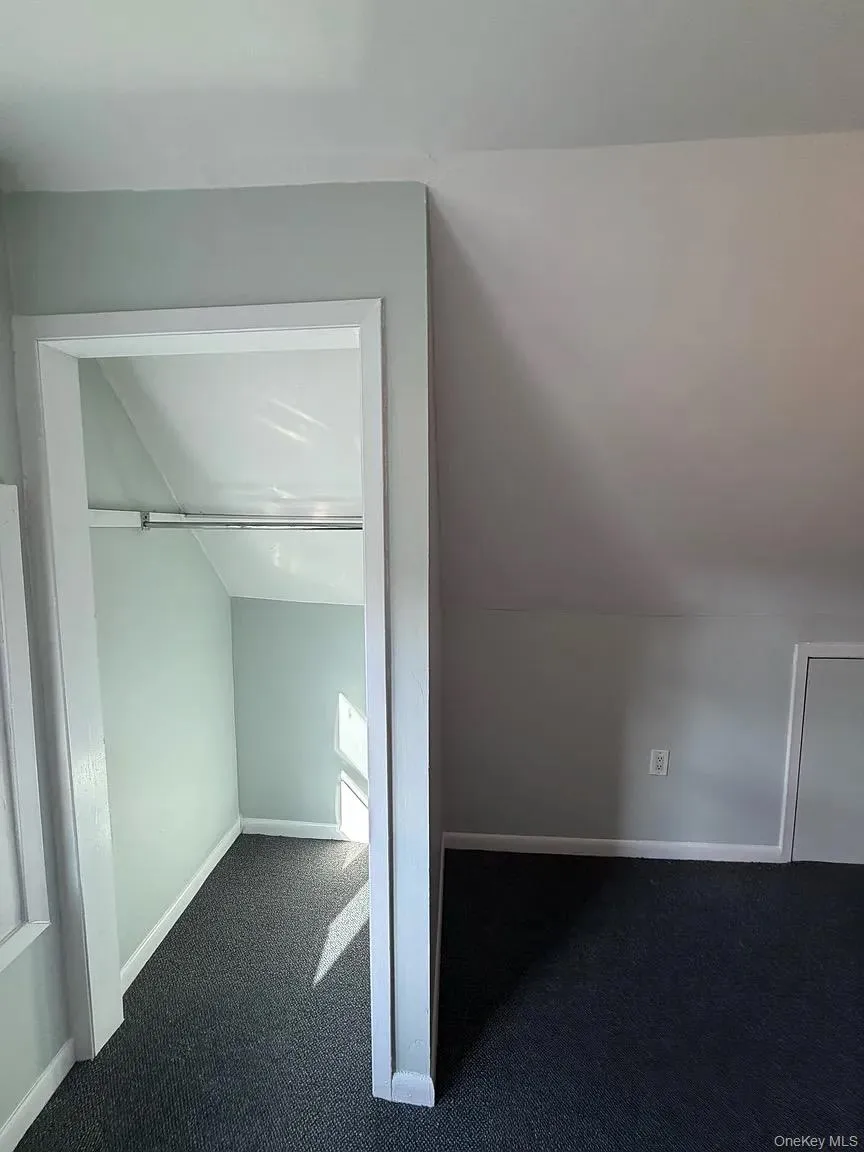 Bonus room featuring dark carpet and vaulted ceiling Bonus room featuring dark carpet and vaulted ceiling
