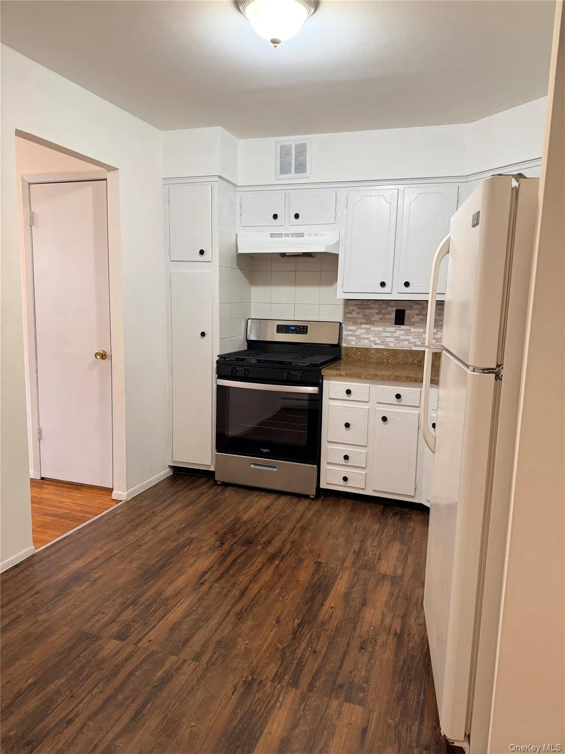 Kitchen with gas stove, white cabinets, tasteful backsplash, and freestanding refrigerator Kitchen with gas stove, white cabinets, tasteful backsplash, and freestanding refrigerator