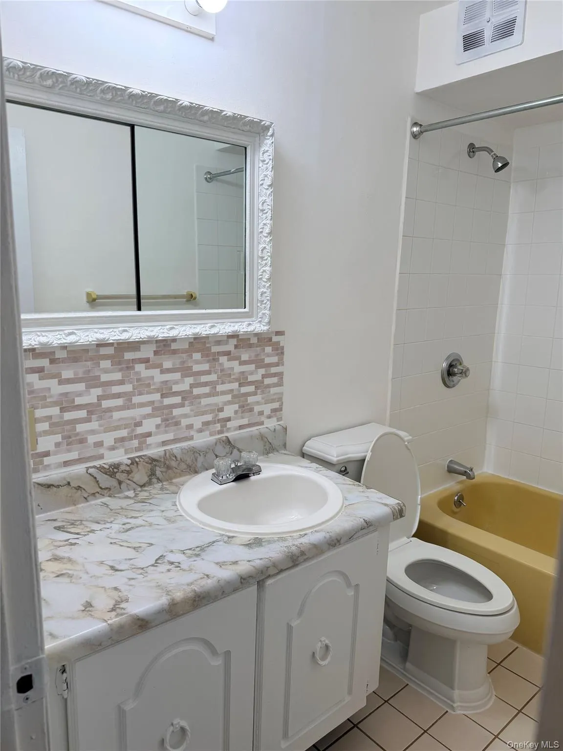 Bathroom with vanity, shower / bathtub combination, light tile patterned flooring, and backsplash Bathroom with vanity, shower / bathtub combination, light tile patterned flooring, and backsplash