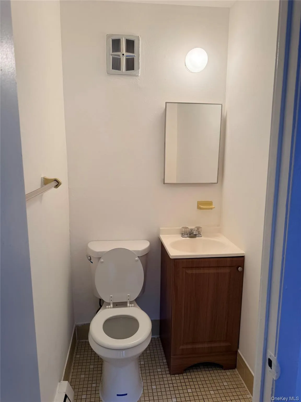 Half bath with vanity, light tile patterned floors, and baseboard heating Half bath with vanity, light tile patterned floors, and baseboard heating