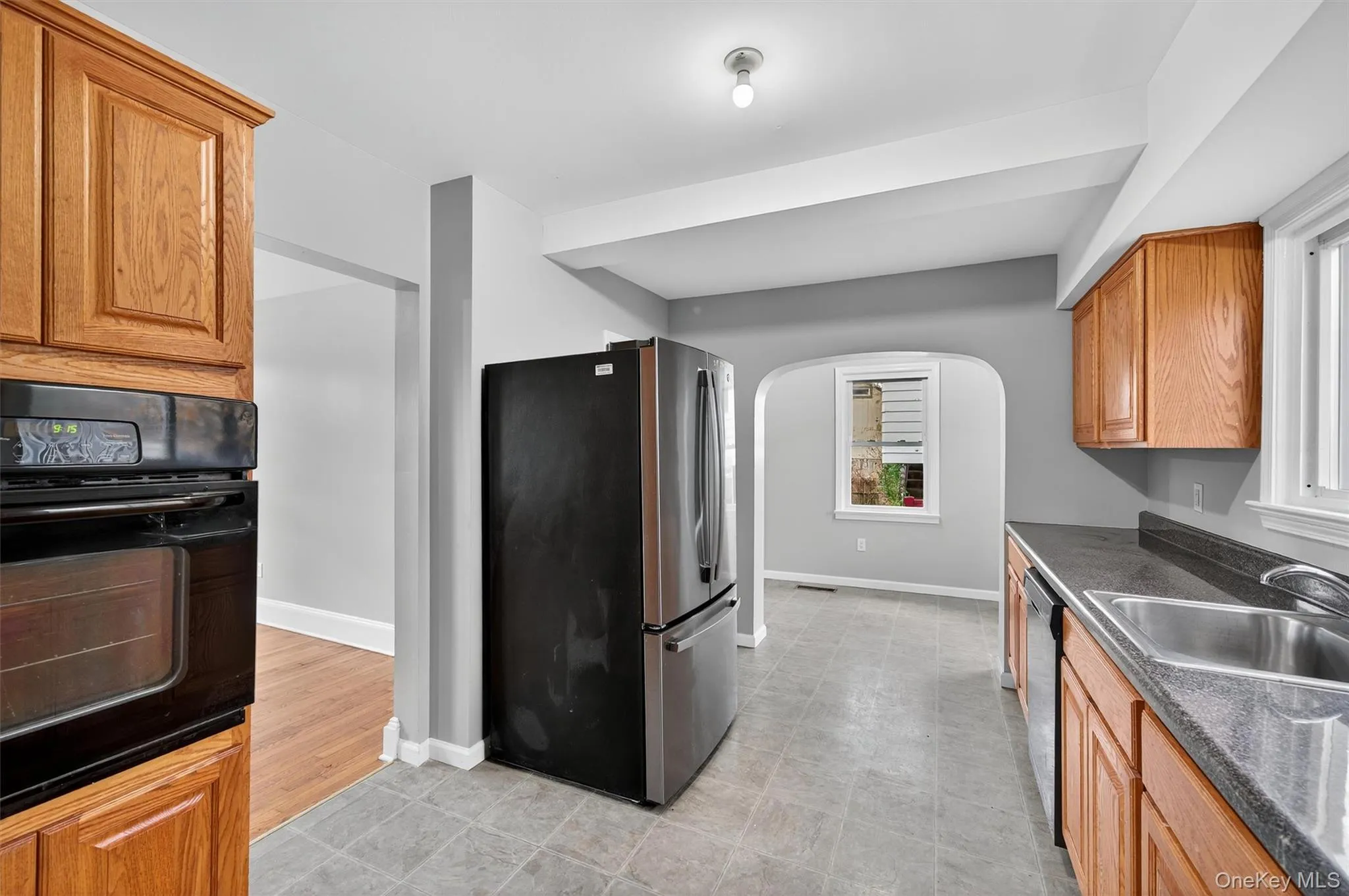 Kitchen featuring black appliances, arched walkways, and brown cabinetry Kitchen featuring black appliances, arched walkways, and brown cabinetry