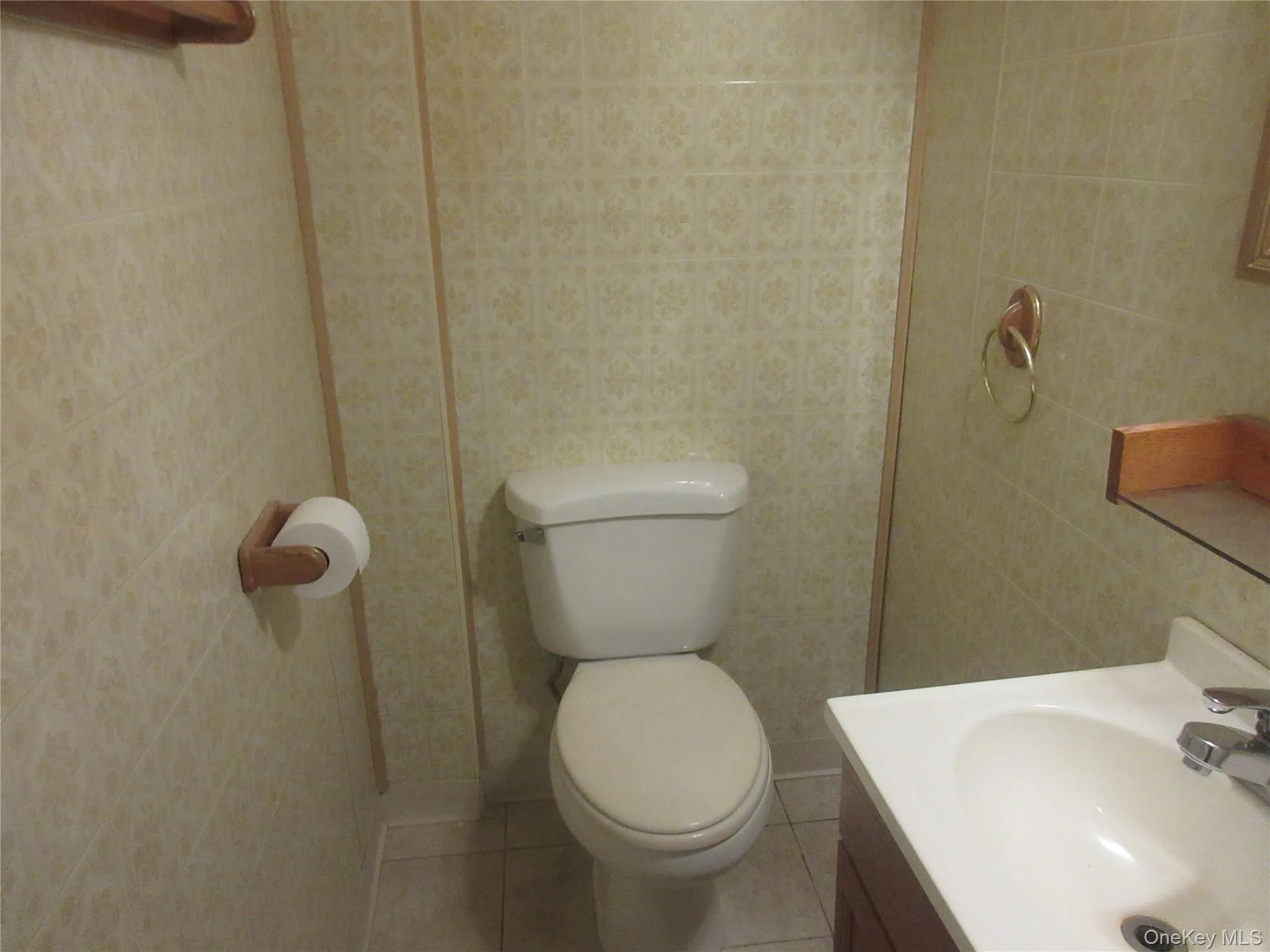 Half bath featuring vanity, light tile patterned floors, and tile walls Half bath featuring vanity, light tile patterned floors, and tile walls