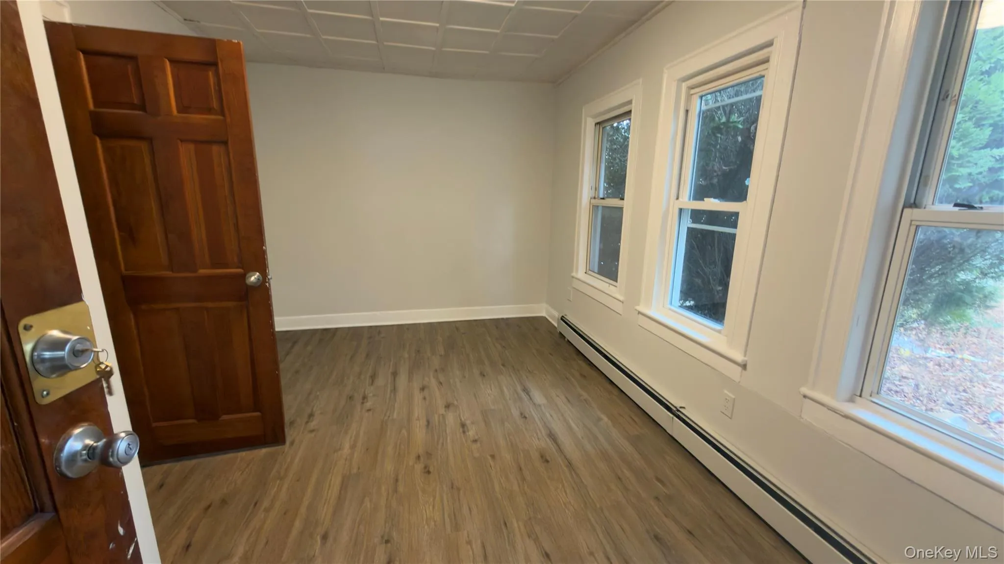 Empty room featuring a baseboard heating unit and wood finished floors Empty room featuring a baseboard heating unit and wood finished floors