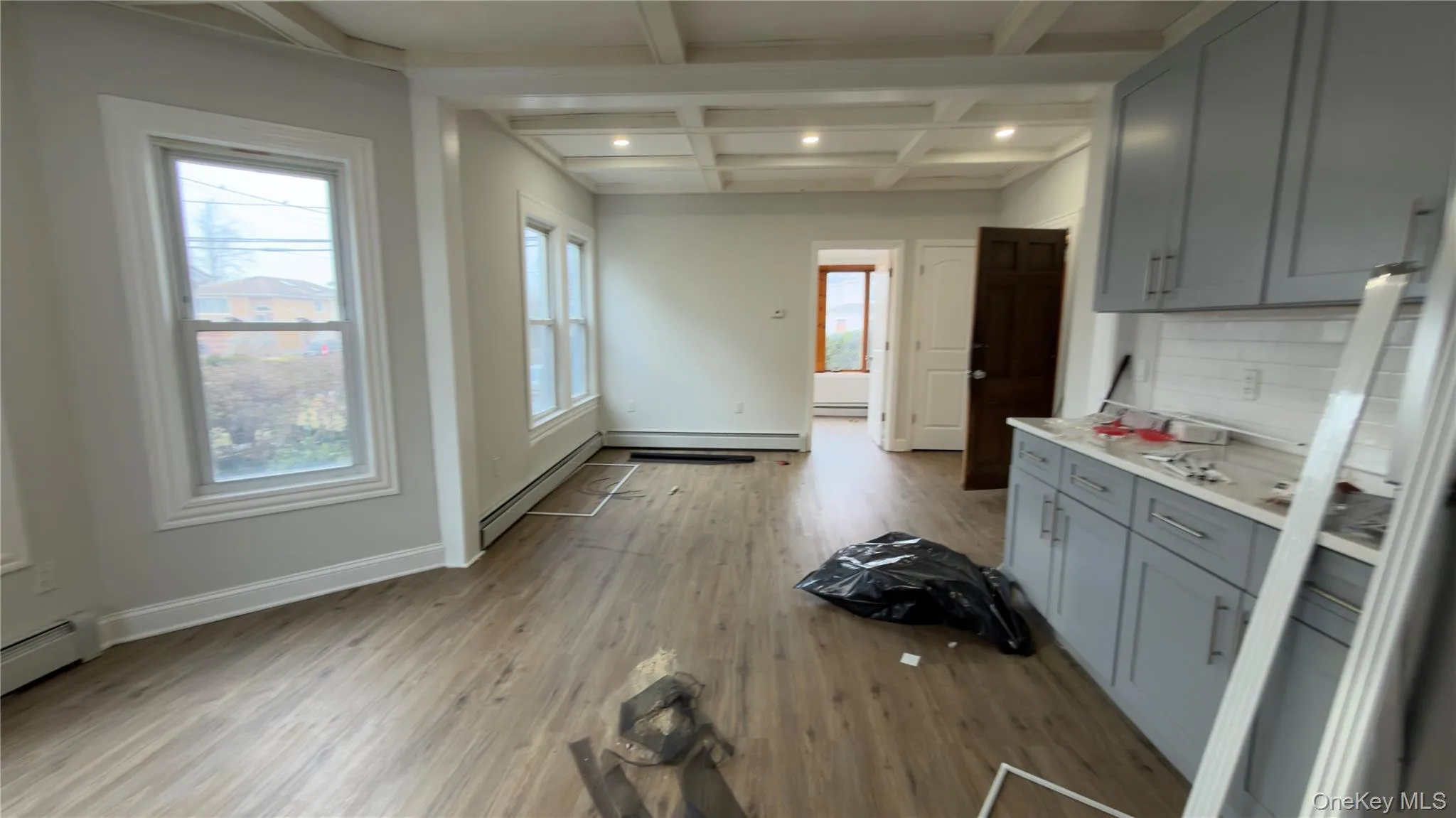 Kitchen featuring gray cabinets, light countertops, beamed ceiling, light wood-style flooring, and coffered ceiling Kitchen featuring gray cabinets, light countertops, beamed ceiling, light wood-style flooring, and coffered ceiling