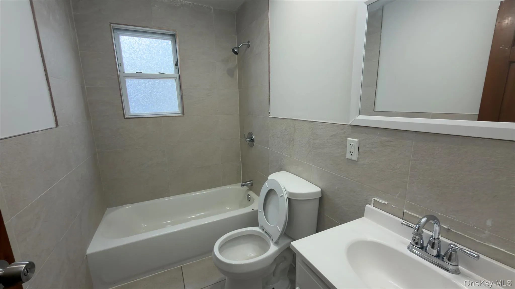 Bathroom with tile walls, vanity, shower / bathtub combination, and tile patterned floors Bathroom with tile walls, vanity, shower / bathtub combination, and tile patterned floors