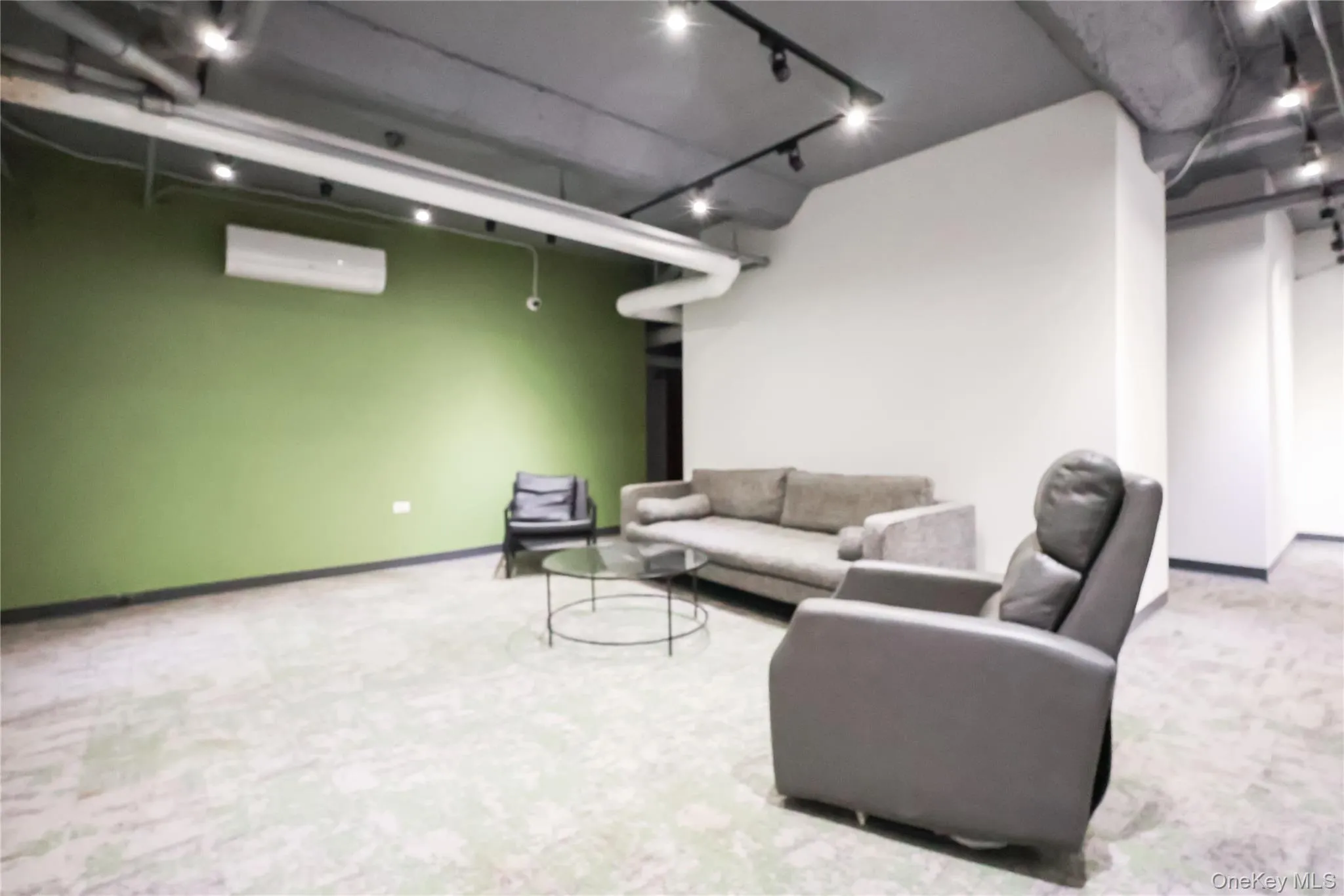 Lounge featuring track lighting, light carpet, and a wall mounted AC Lounge featuring track lighting, light carpet, and a wall mounted AC