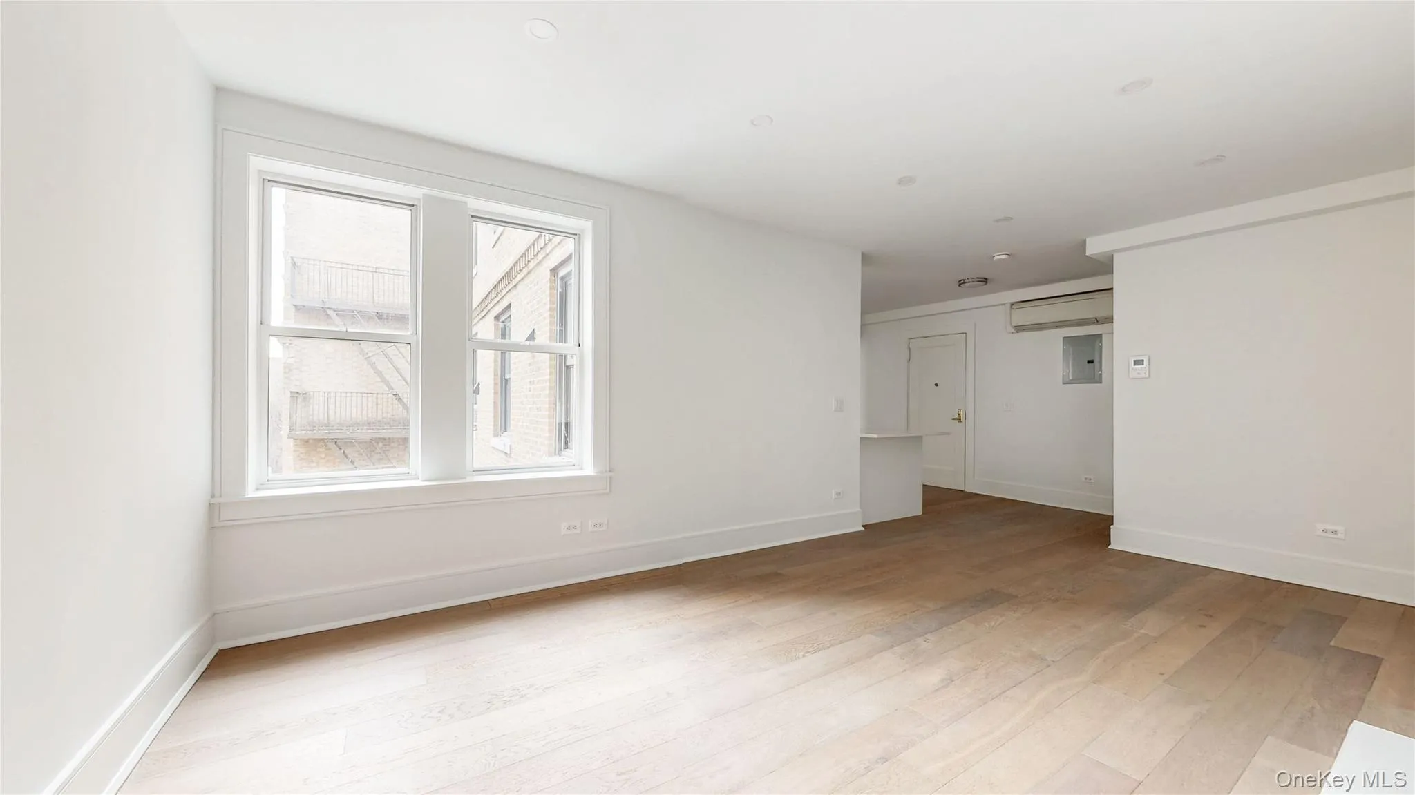 Living room featuring light wood-style flooring, a wall mounted air conditioner. Living room featuring light wood-style flooring, a wall mounted air conditioner.