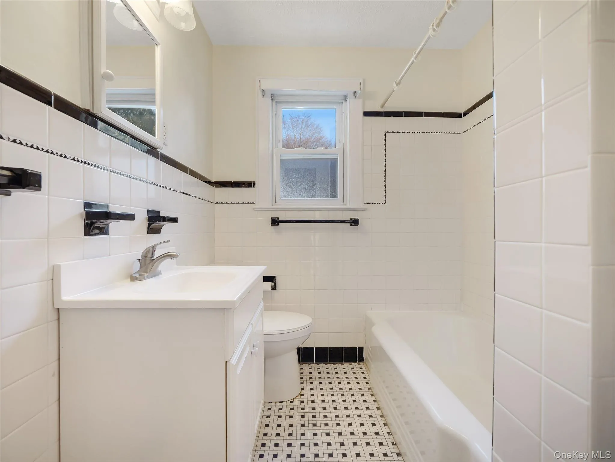 Full bathroom with vanity, shower / bath combination, and tile walls Full bathroom with vanity, shower / bath combination, and tile walls