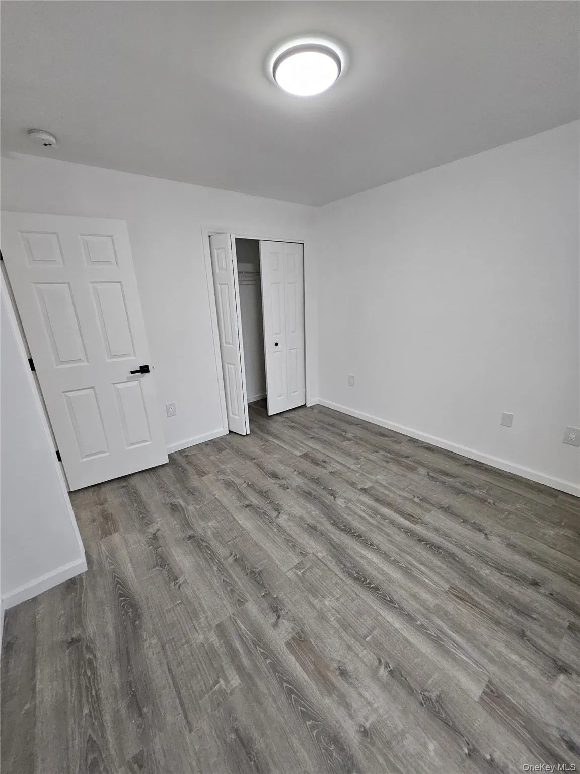 Unfurnished bedroom featuring wood finished floors and a closet Unfurnished bedroom featuring wood finished floors and a closet