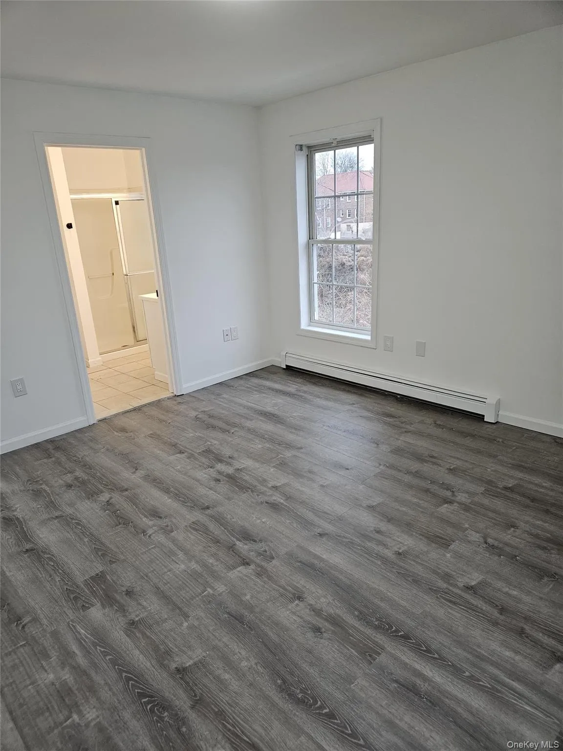 Unfurnished room with baseboard heating and wood finished floors Unfurnished room with baseboard heating and wood finished floors