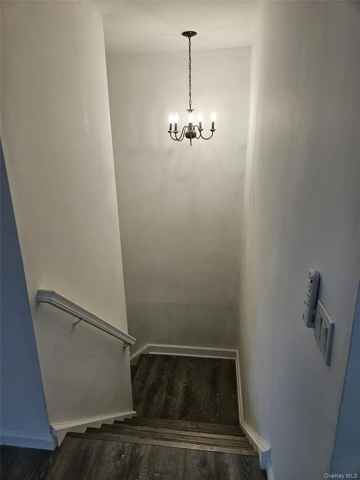 Stairs featuring wood finished floors and a chandelier Stairs featuring wood finished floors and a chandelier