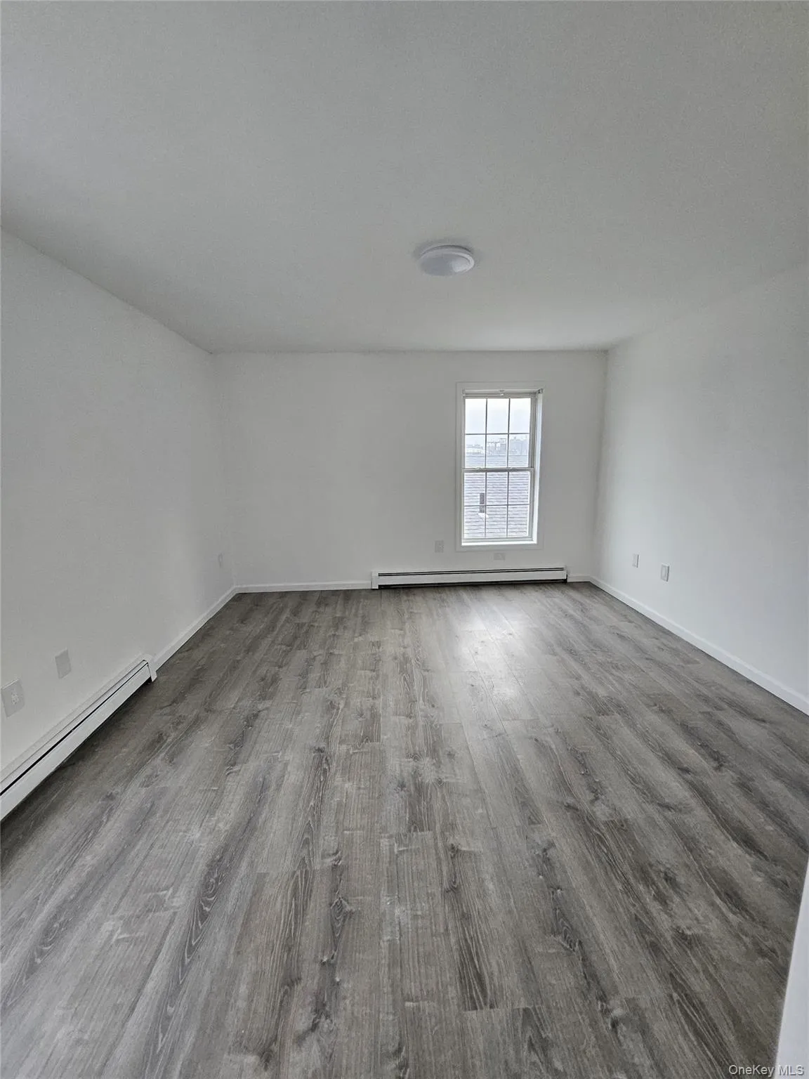 Empty room with a baseboard heating unit and light wood finished floors Empty room with a baseboard heating unit and light wood finished floors