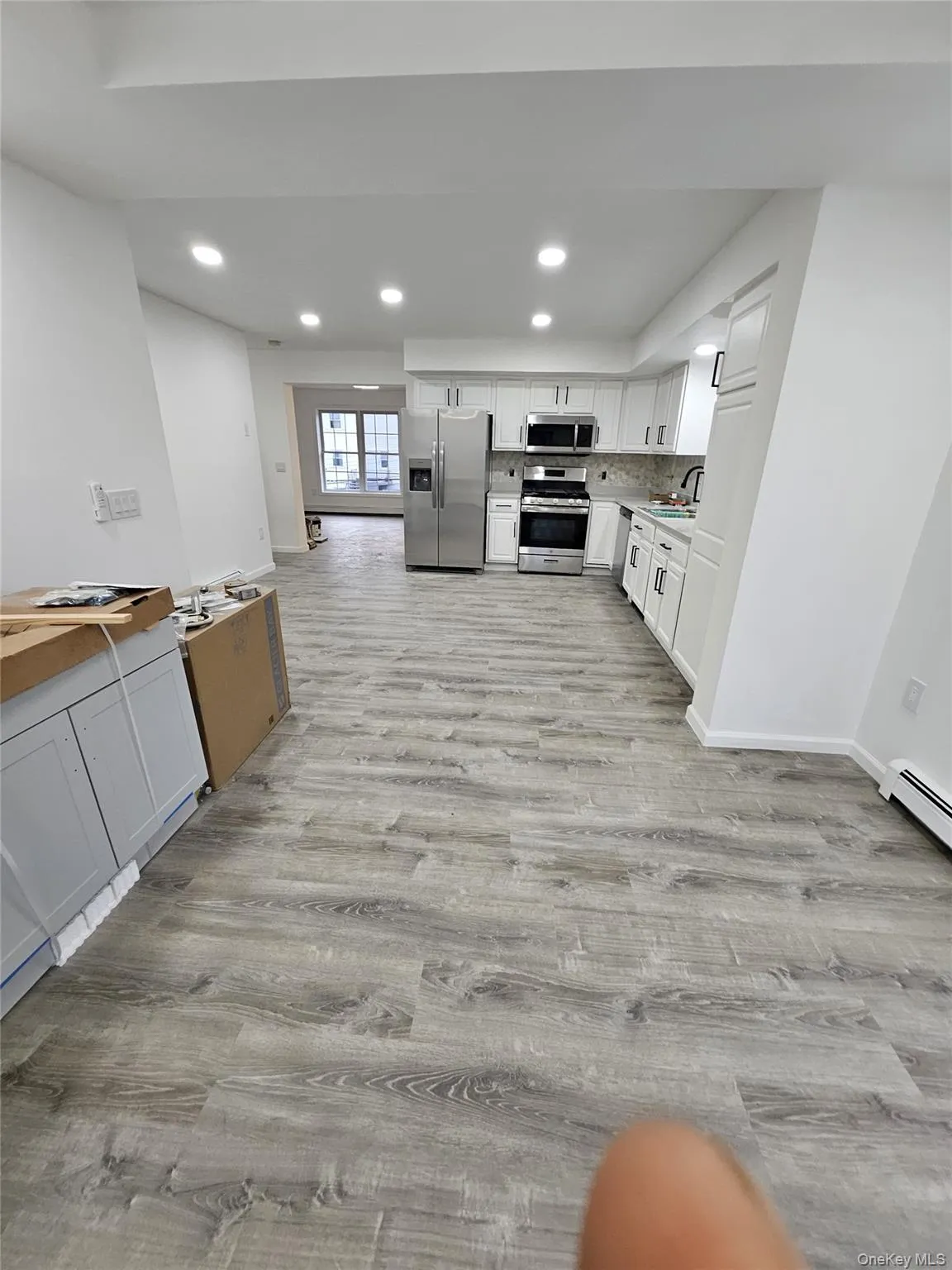 Kitchen featuring white cabinets, recessed lighting, light countertops, appliances with stainless steel finishes, and baseboard heating Kitchen featuring white cabinets, recessed lighting, light countertops, appliances with stainless steel finishes, and baseboard heating