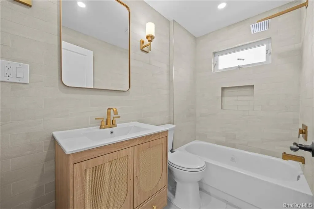 Bathroom featuring vanity, tile walls, and shower combination Bathroom featuring vanity, tile walls, and shower combination