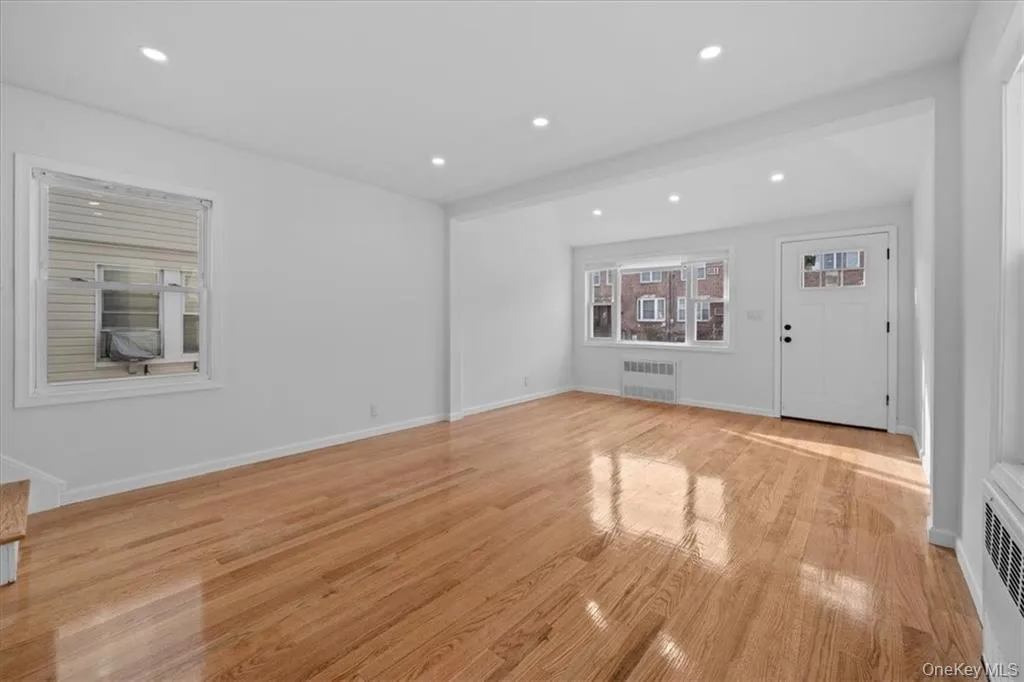 Unfurnished living room with light wood-style floors, radiator, and recessed lighting Unfurnished living room with light wood-style floors, radiator, and recessed lighting