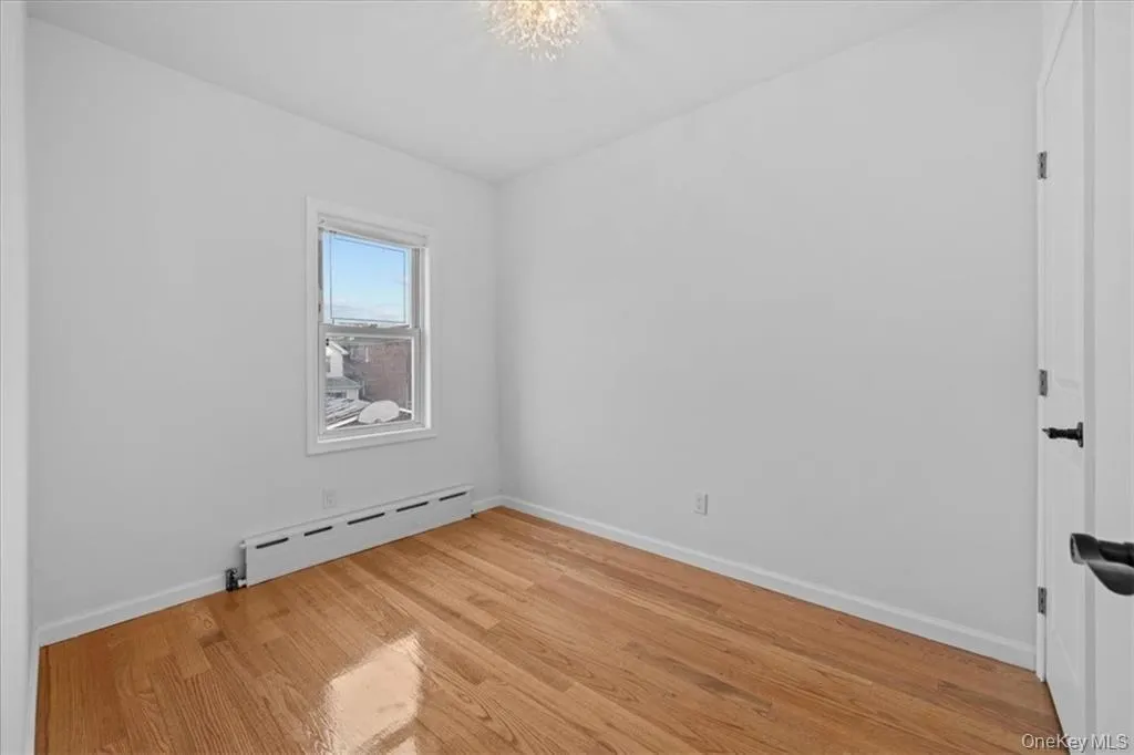 Empty room featuring a baseboard radiator and light wood-style floors Empty room featuring a baseboard radiator and light wood-style floors