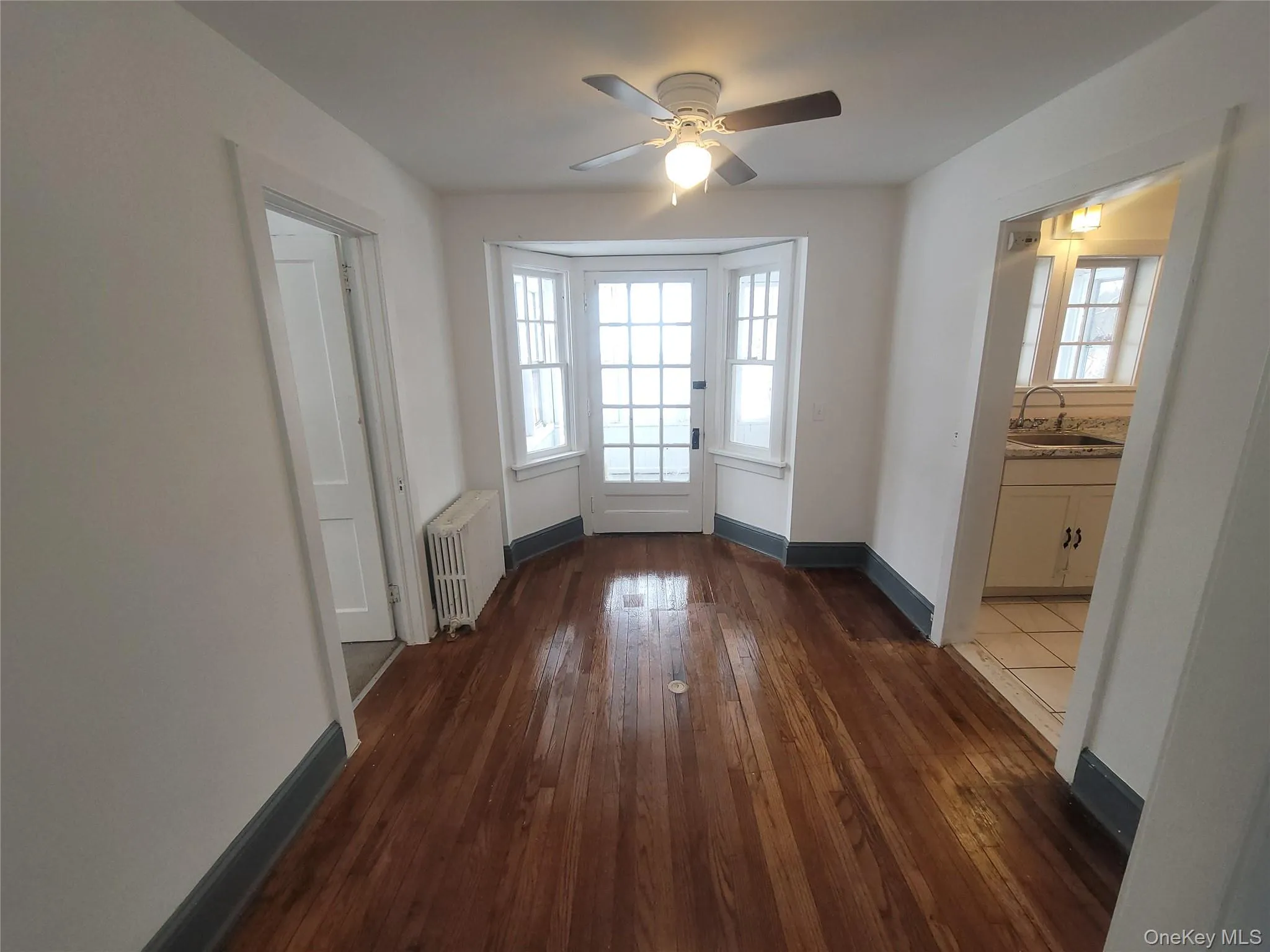 Entryway featuring radiator, wood-type flooring, and ceiling fan Entryway featuring radiator, wood-type flooring, and ceiling fan