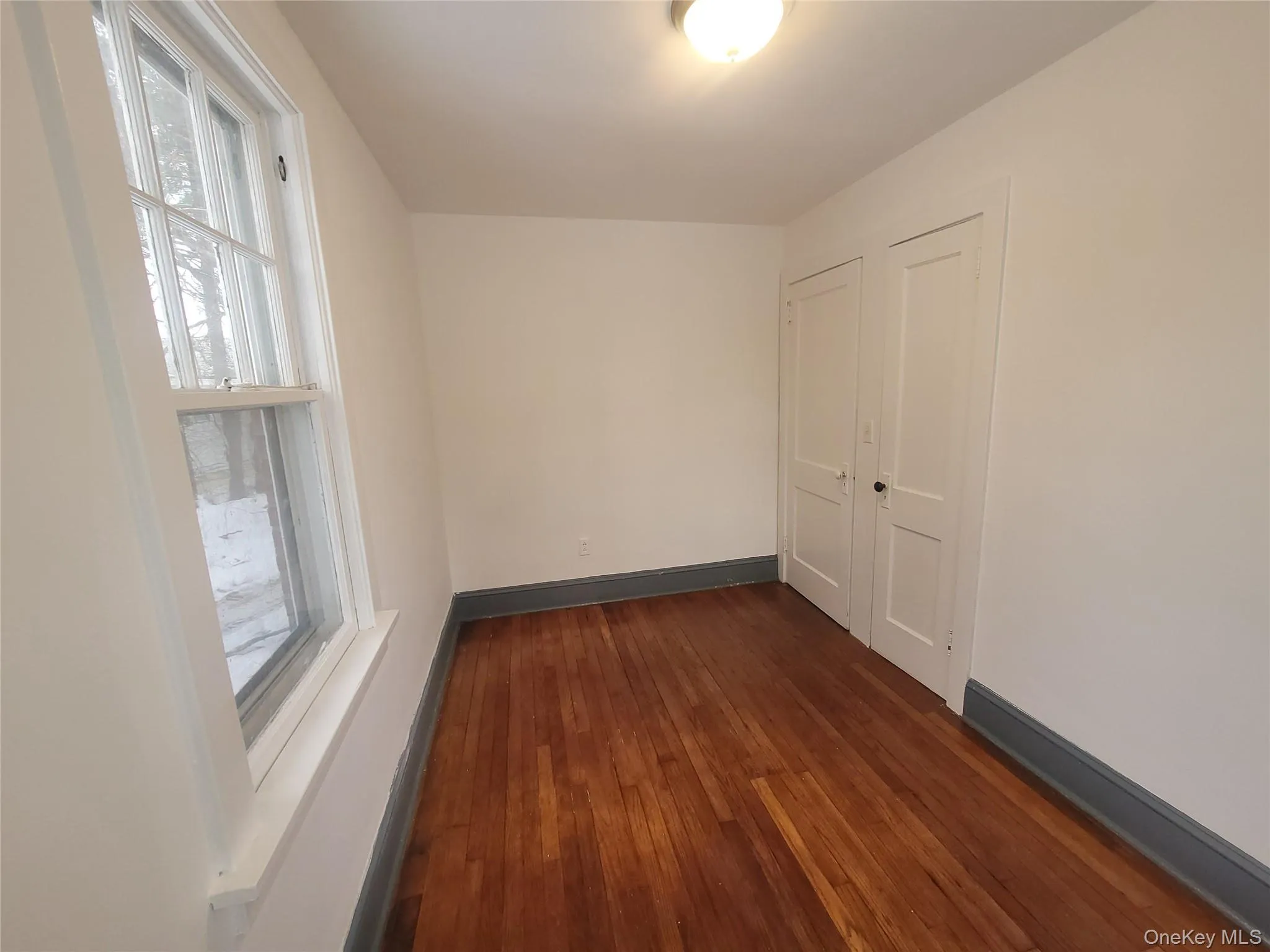 Spare room with baseboards and dark wood-style flooring Spare room with baseboards and dark wood-style flooring