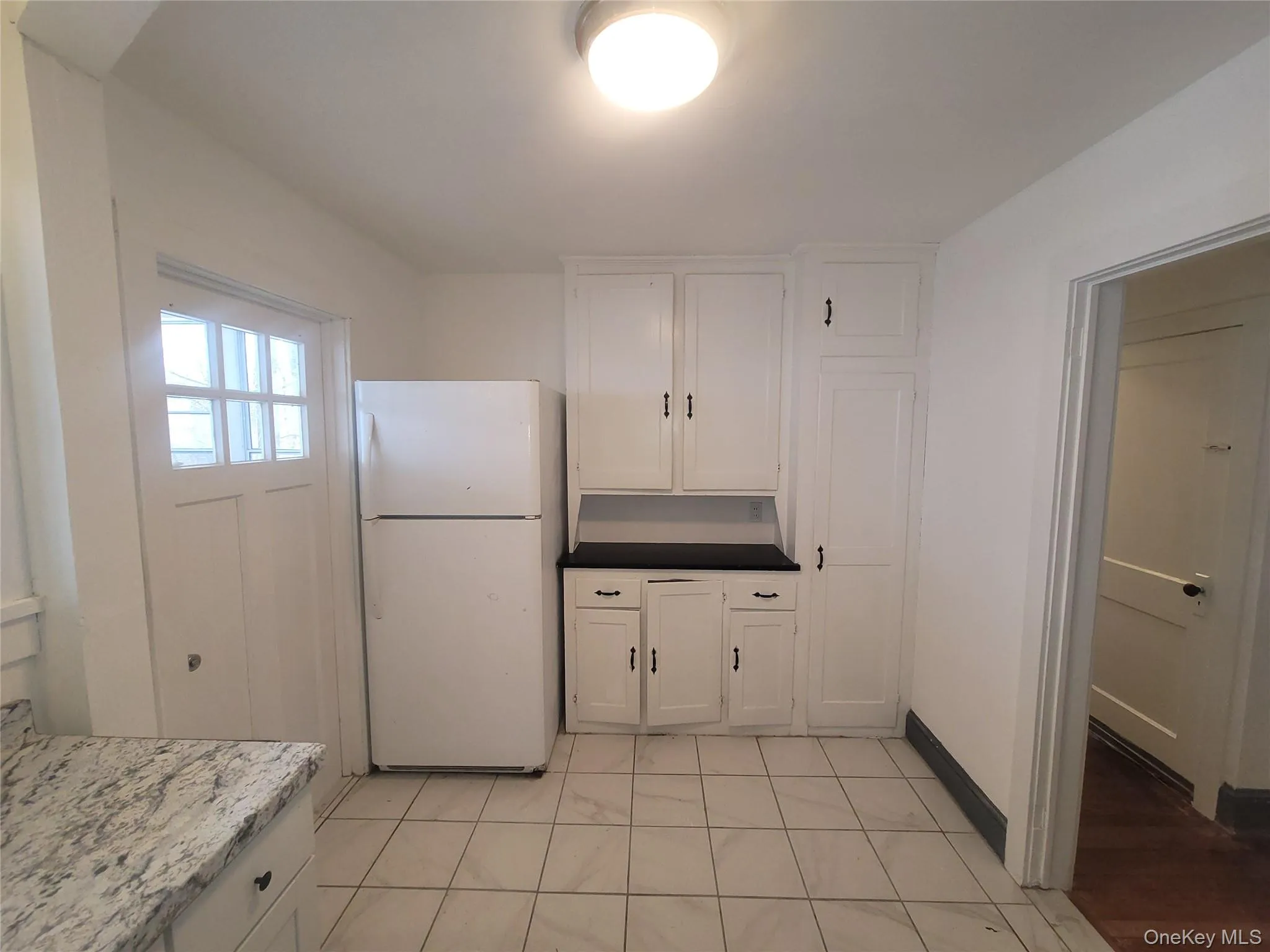 Kitchen with white cabinetry and freestanding refrigerator Kitchen with white cabinetry and freestanding refrigerator