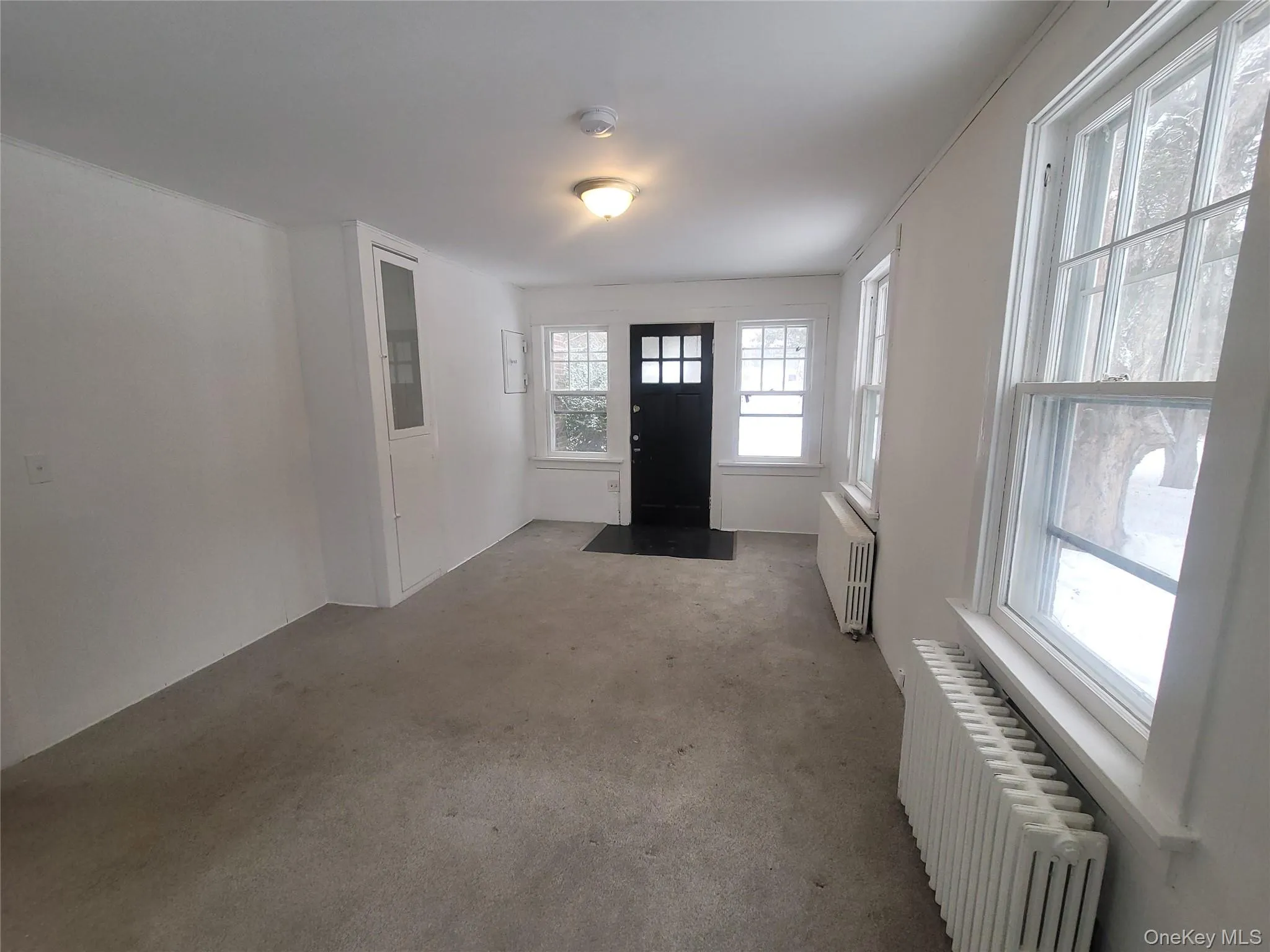 Carpeted foyer featuring radiator heating unit Carpeted foyer featuring radiator heating unit