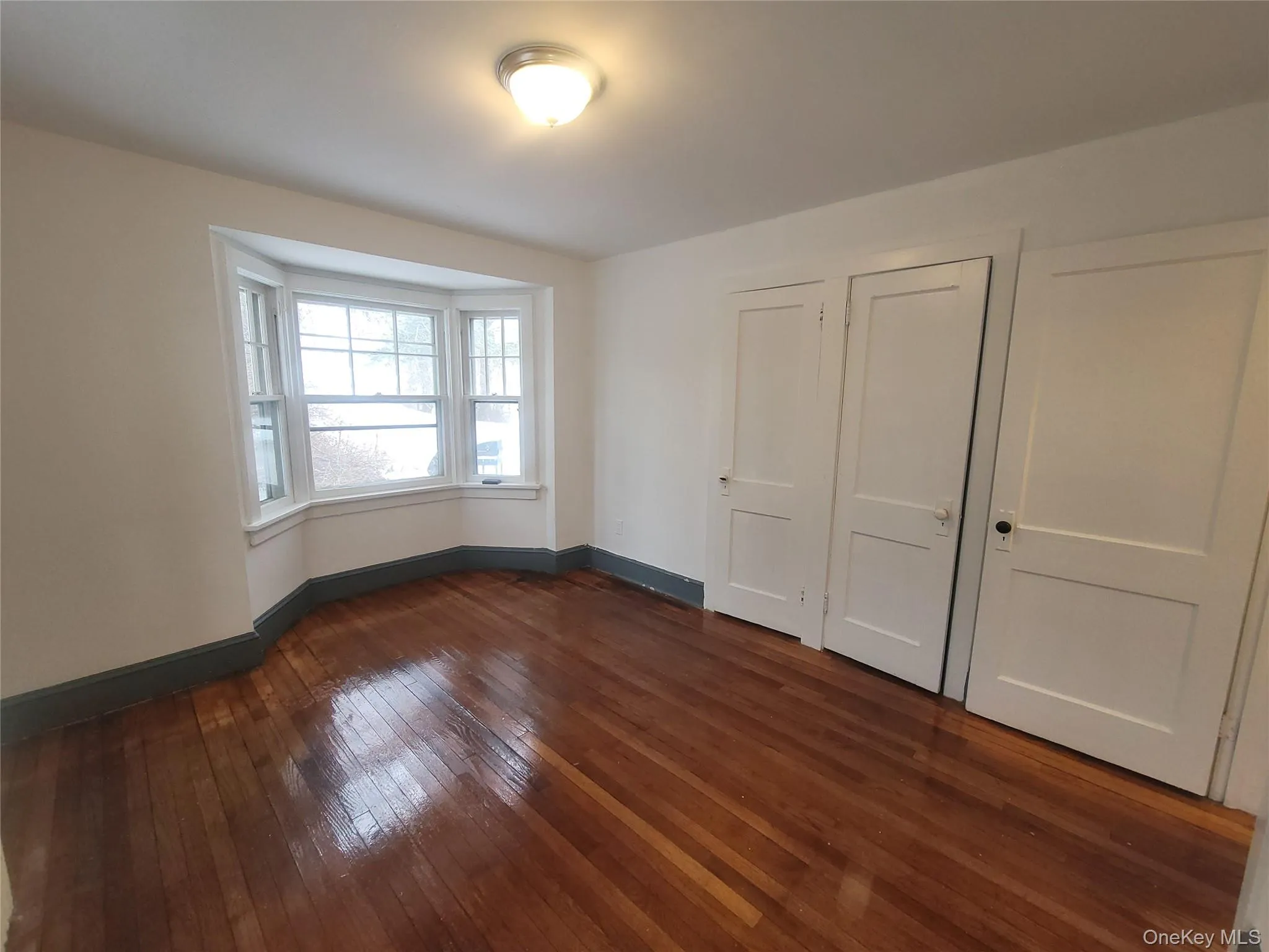 Unfurnished bedroom featuring dark wood-style flooring and a closet Unfurnished bedroom featuring dark wood-style flooring and a closet