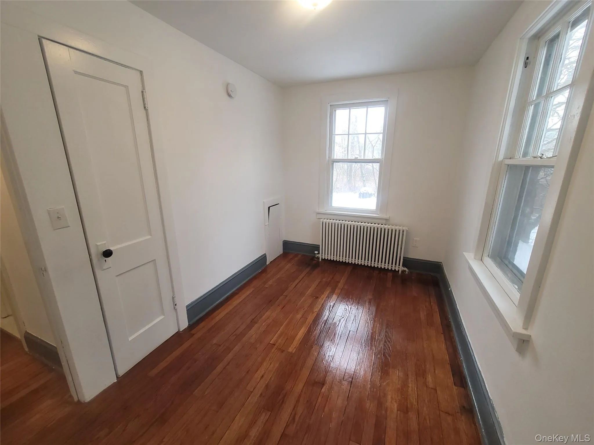 Empty room featuring radiator and dark wood-style flooring Empty room featuring radiator and dark wood-style flooring