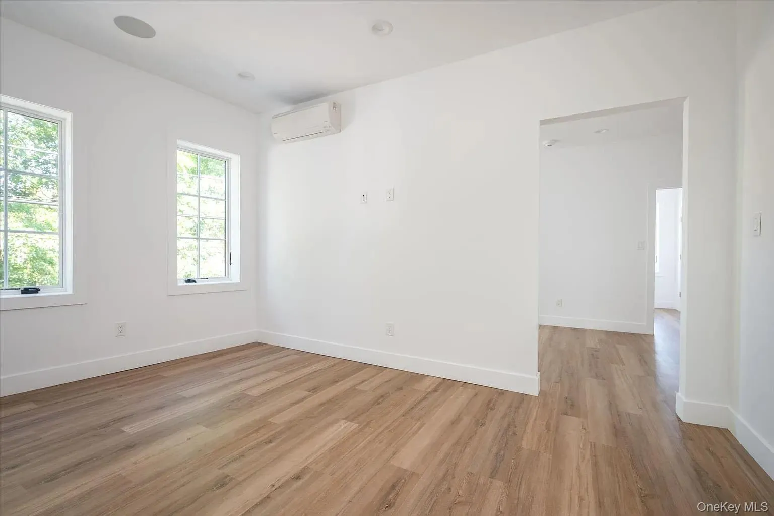 Empty room with light wood finished floors and a wall mounted air conditioner Empty room with light wood finished floors and a wall mounted air conditioner