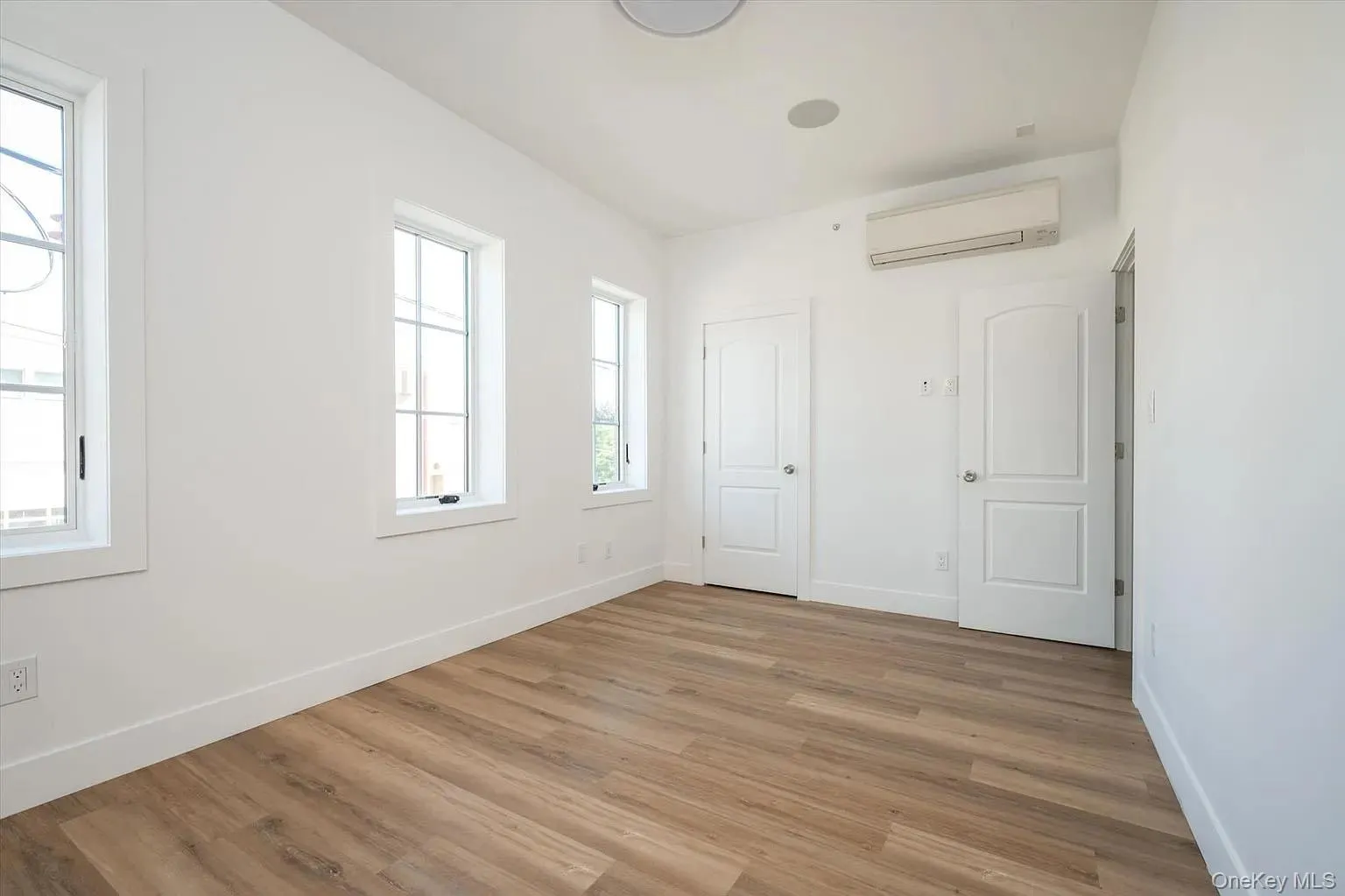 Unfurnished bedroom with light wood-style flooring and a wall unit AC Unfurnished bedroom with light wood-style flooring and a wall unit AC