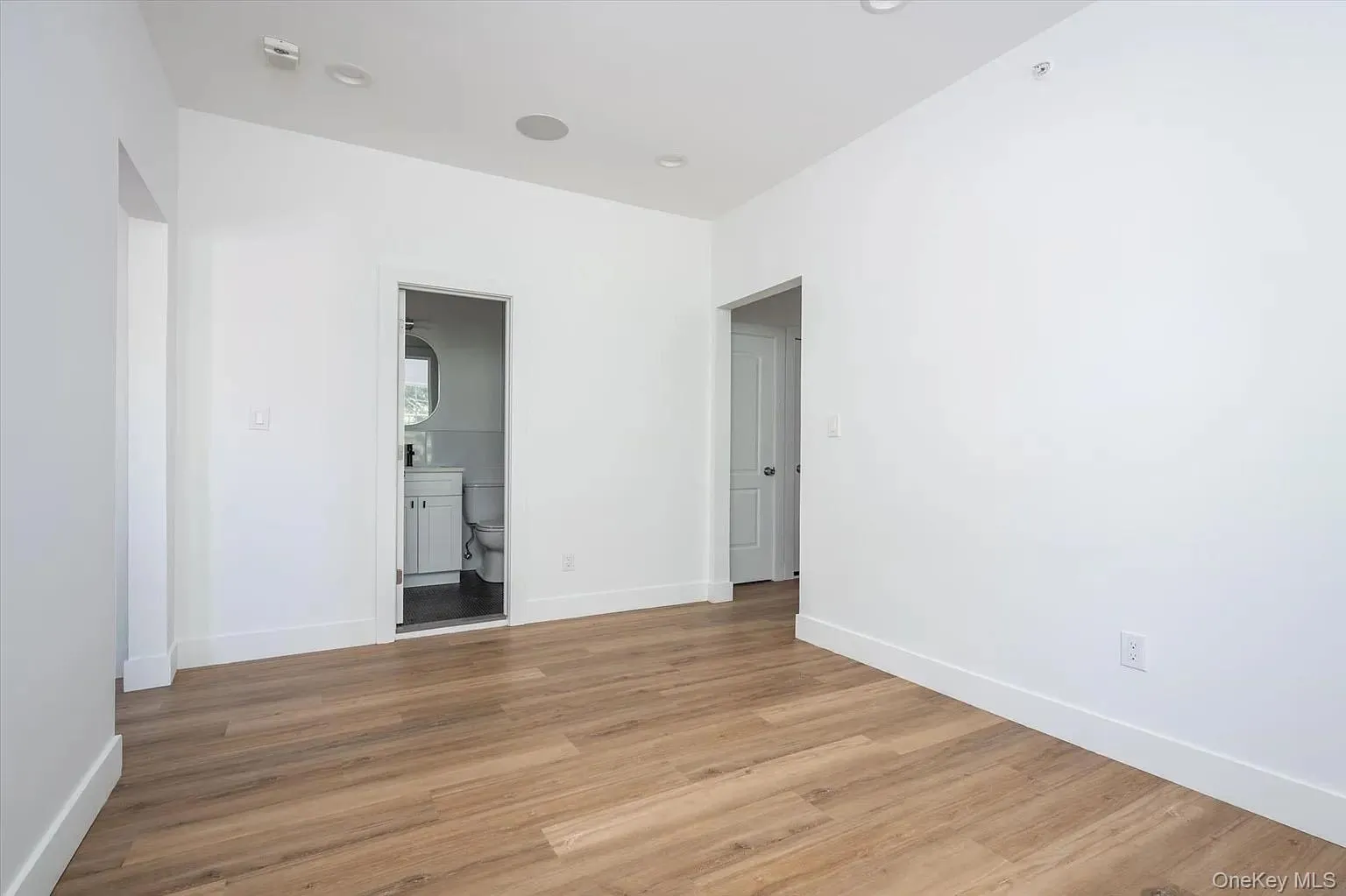 Unfurnished bedroom with light wood-style flooring and ensuite bathroom Unfurnished bedroom with light wood-style flooring and ensuite bathroom