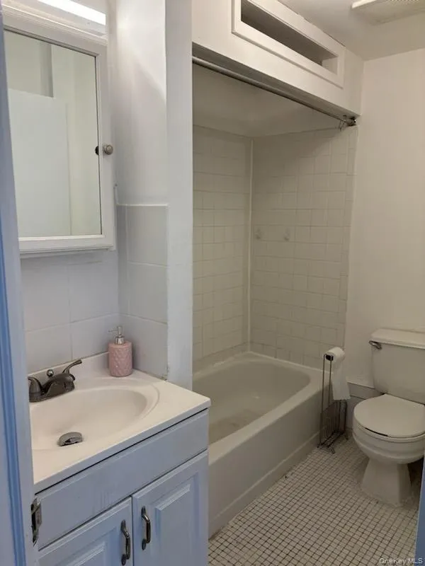 Full bath featuring vanity, light tile patterned flooring, and shower / bath combination Full bath featuring vanity, light tile patterned flooring, and shower / bath combination