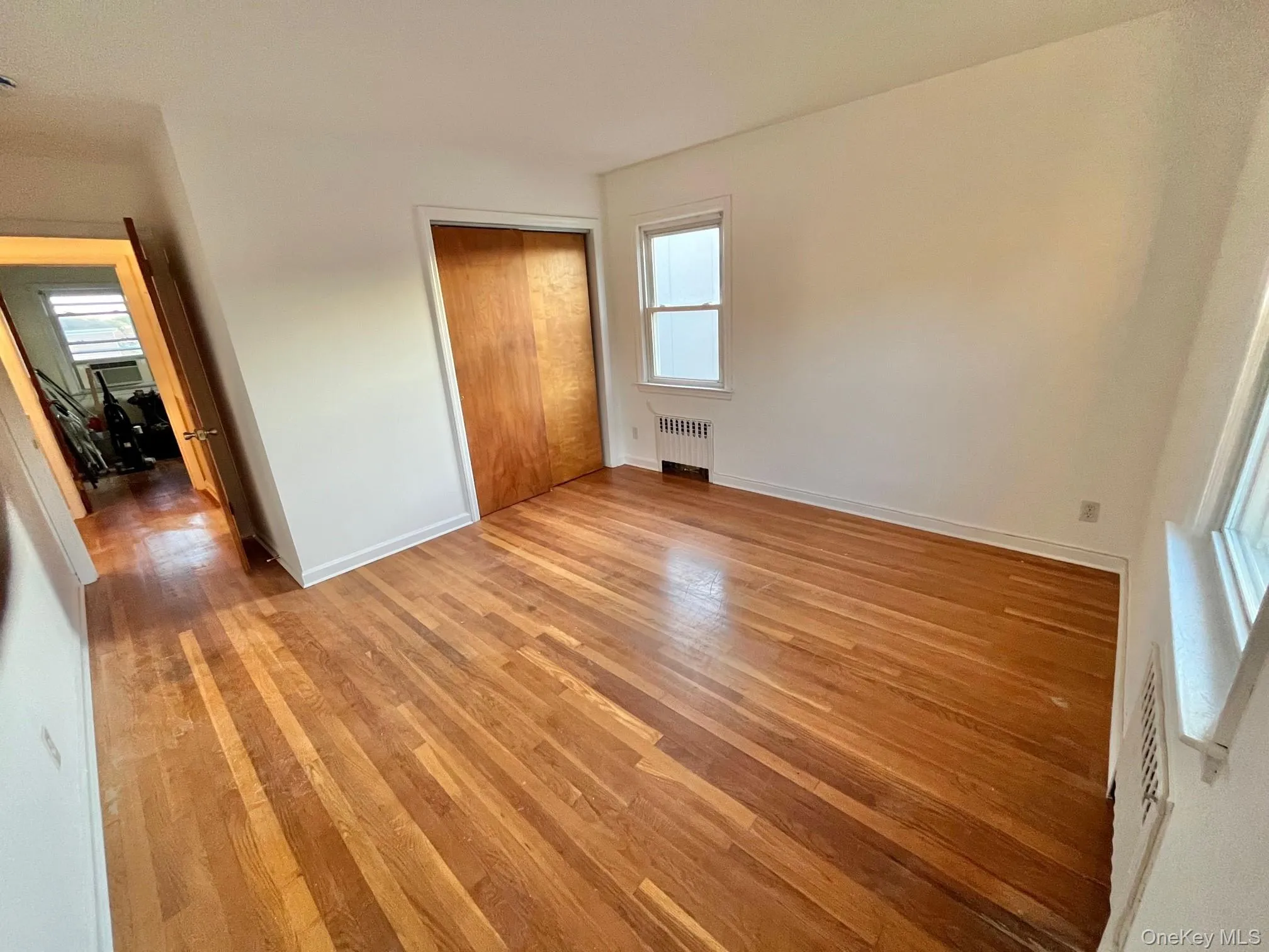 Unfurnished bedroom featuring a closet, light wood-type flooring, and radiator Unfurnished bedroom featuring a closet, light wood-type flooring, and radiator