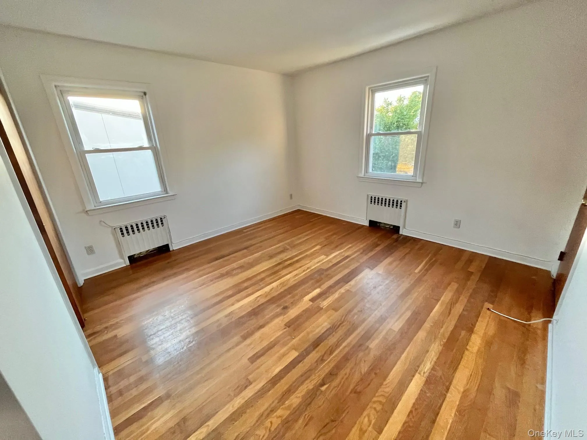 Empty room featuring light wood finished floors and radiator heating unit Empty room featuring light wood finished floors and radiator heating unit