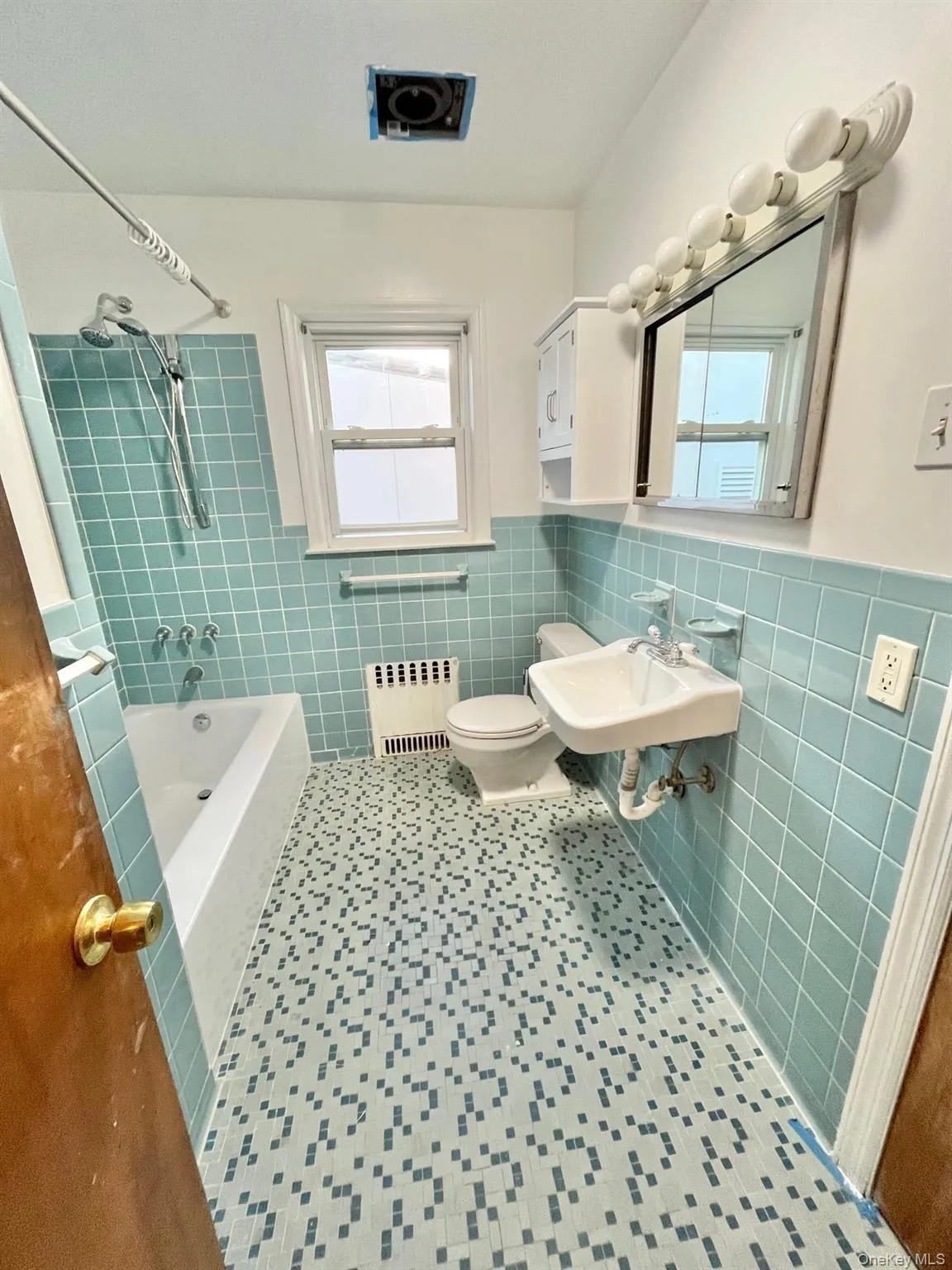 Full bath featuring wainscoting, radiator, shower combination, tile walls, and tile patterned floors Full bath featuring wainscoting, radiator, shower combination, tile walls, and tile patterned floors